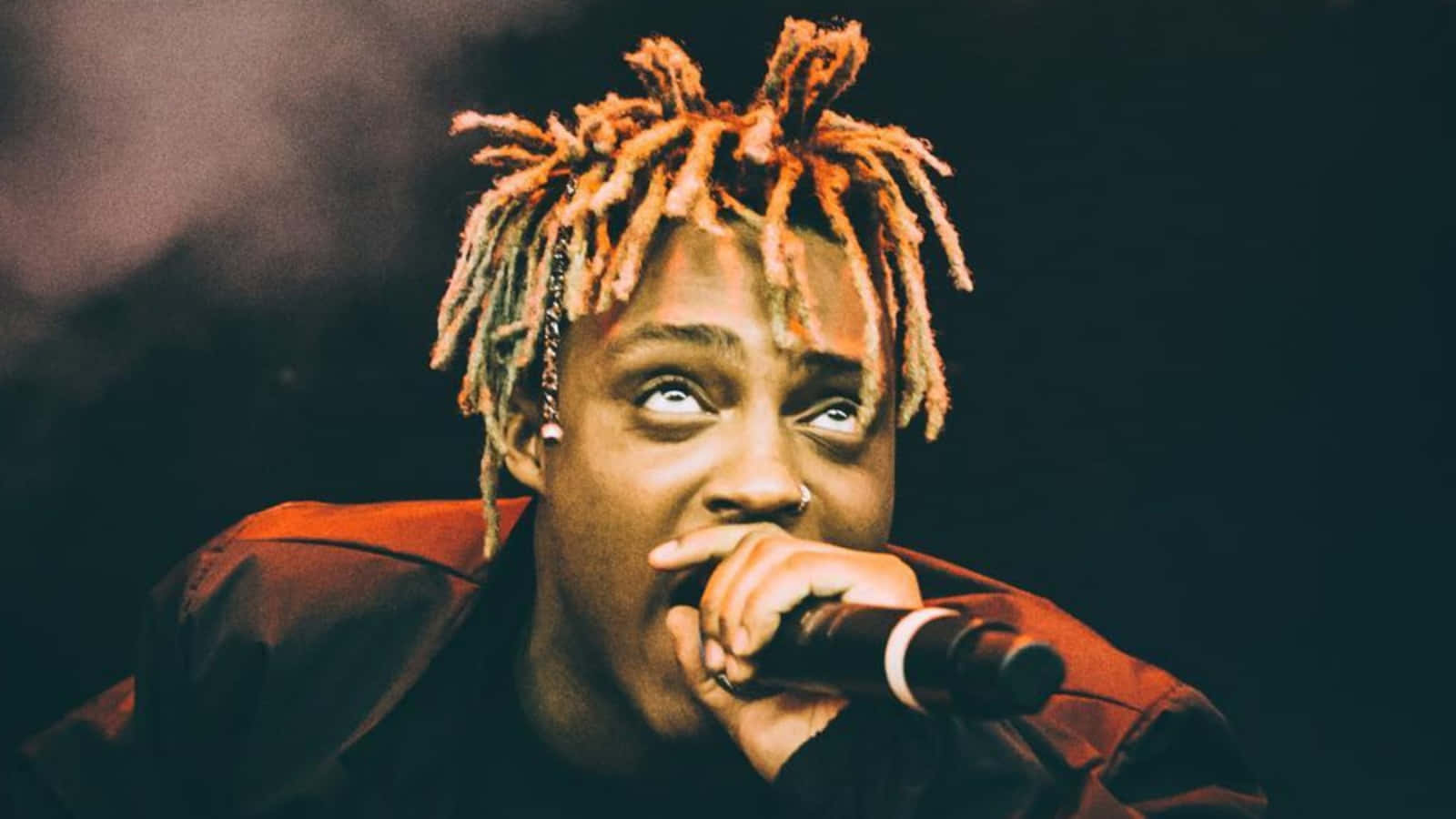 橙色辮子說唱歌手在舞台上手持麥克風表演 — Juice Wrld 壁紙
