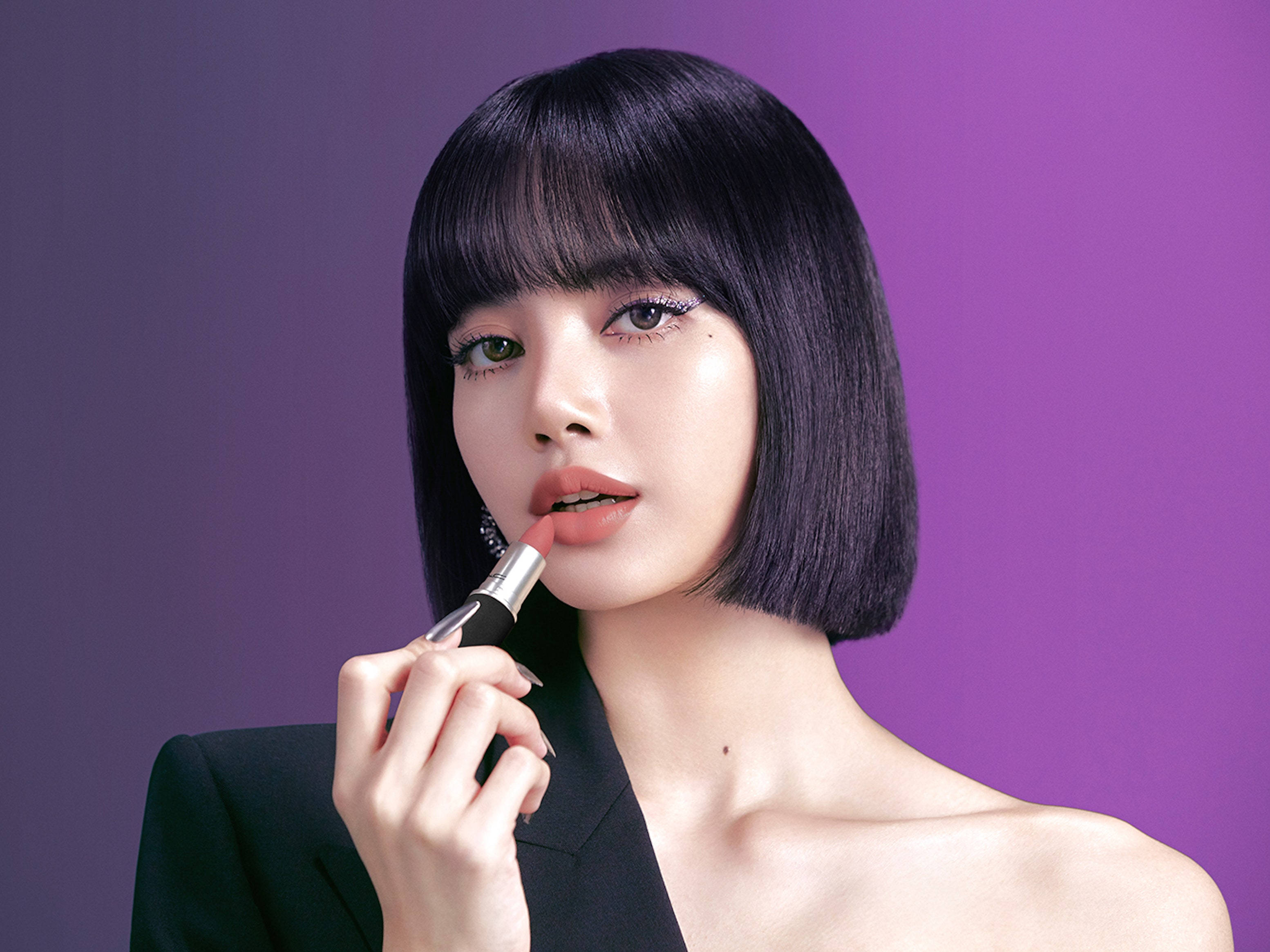 Lalisa 桌布 壁紙 — 一位擁有光滑黑色鮑伯頭和大膽眼線的女性，在漸變紫色背景下塗抹珊瑚色唇膏。