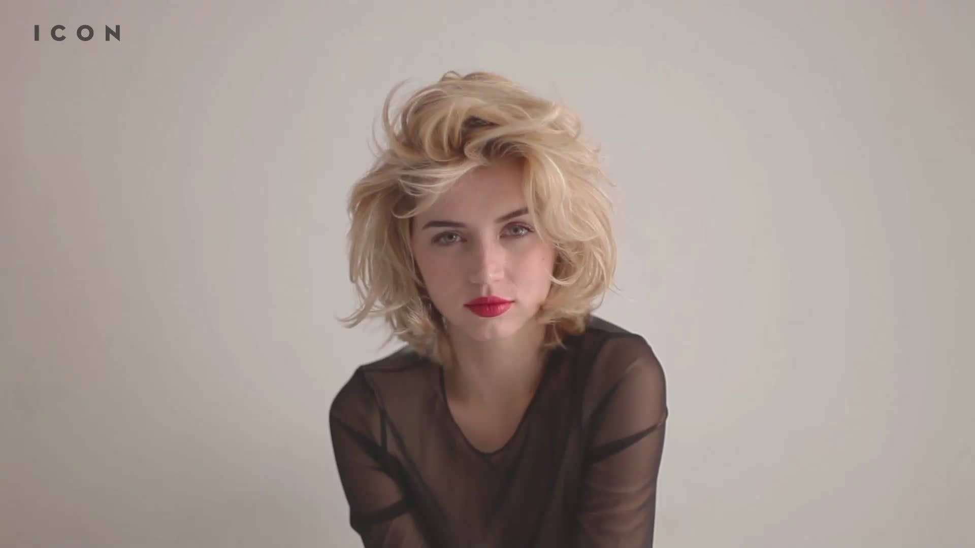 ana de armas 桌布 壁紙 — 一位擁有凌亂金髮和大膽紅唇的女性，在純米白色背景下直視鏡頭。