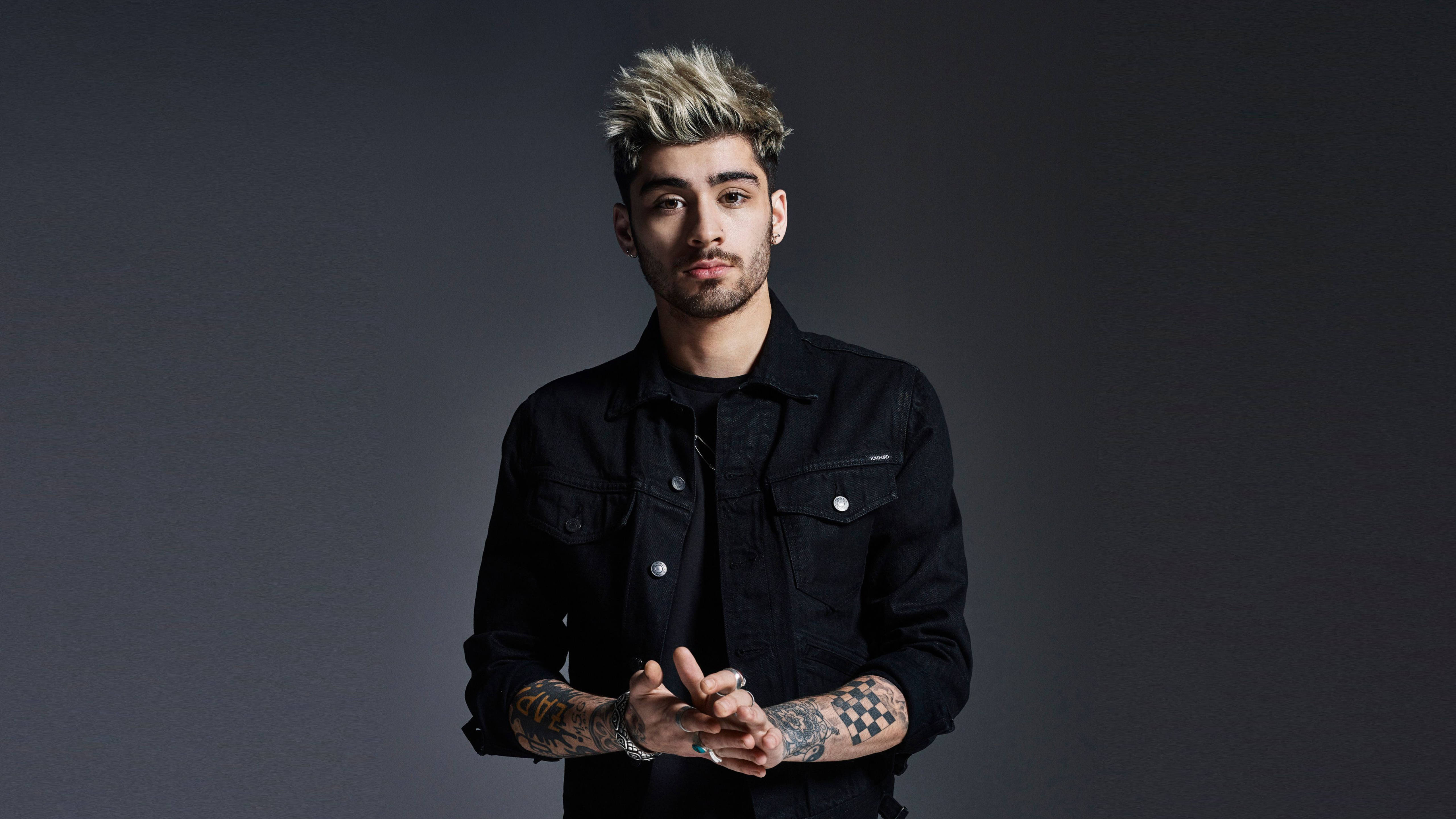 zayn 桌布 壁紙 — 一位擁有尖刺金髮和刺青的年輕男子，在深灰色攝影棚背景前自信地凝視著鏡頭。