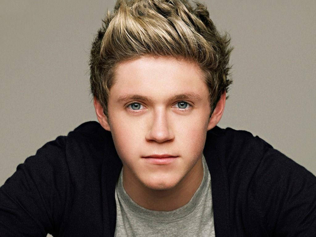 niall horan 桌布 壁紙 — 一位擁有尖刺金髮和強烈藍眼睛的年輕男子在工作室肖像中直視鏡頭。