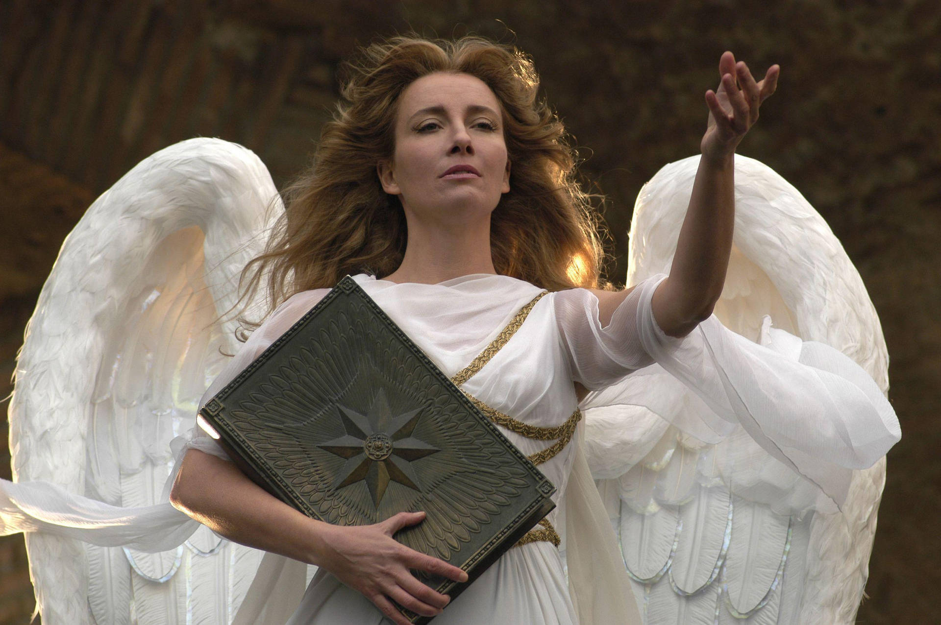 Angel 桌布 壁紙 — 一位擁有巨大白色羽毛翅膀的女性在森林中舉起一隻手，手持一本帶有星星浮雕的書。