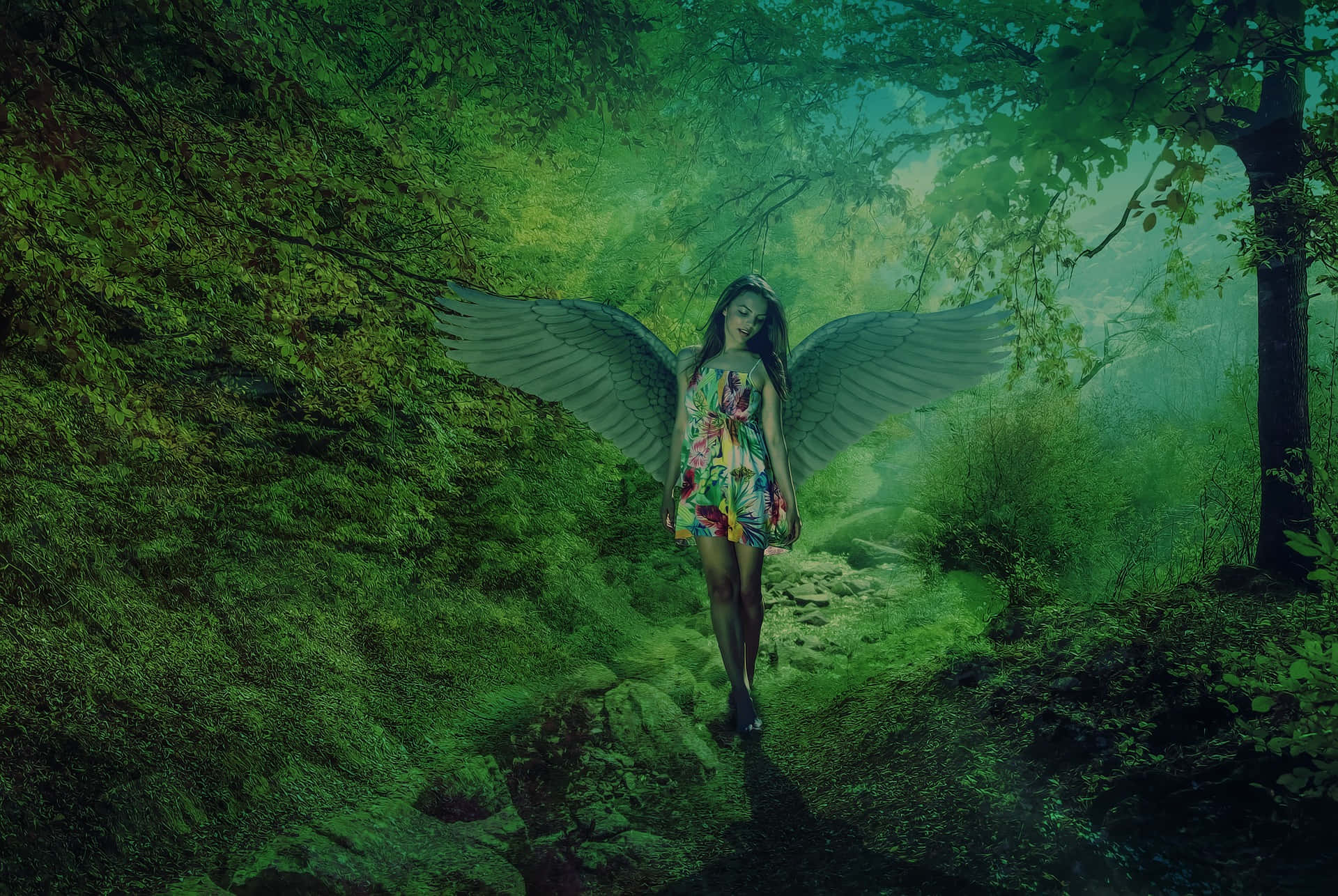 仙女 桌布 壁紙 — 一位擁有巨大羽毛翅膀的女人，沿著一條長滿苔蘚的森林小徑行走，沐浴在空靈的綠光中。
