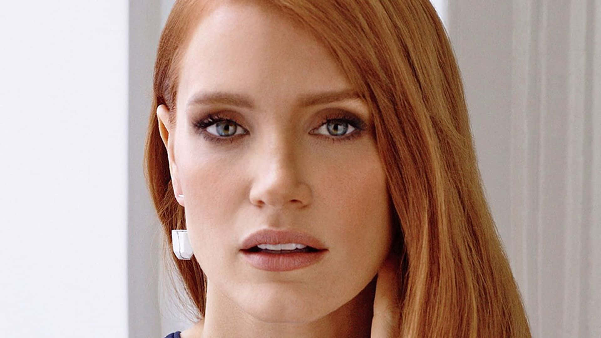 jessica chastain 桌布 壁紙 — 一位擁有引人注目的紅髮和銳利藍眼的女性特寫肖像，直視鏡頭。