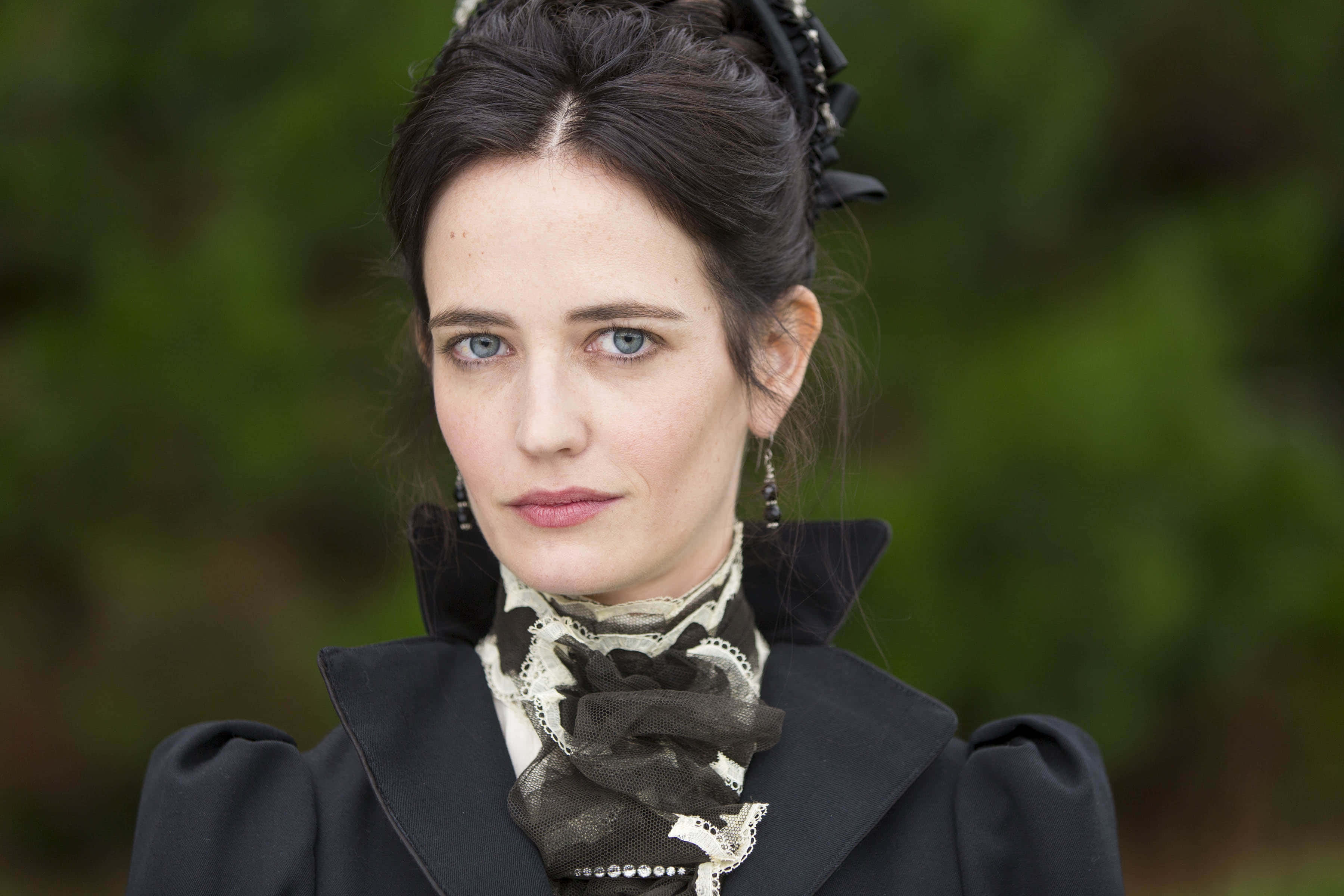 eva green 桌布 壁紙 — 一位擁有引人注目的藍色眼睛和深色頭髮、梳著優雅高髻的女性直視鏡頭，穿著帶有蕾絲和珍珠裝飾的黑色維多利亞風格外套，背景是柔和的綠色模糊效果。