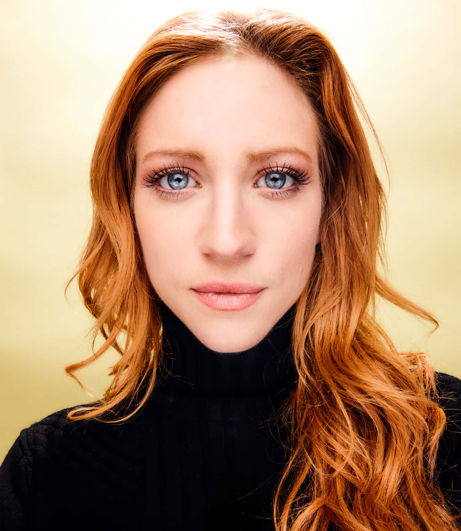 brittany snow 桌布 壁紙 — 一位擁有引人注目的藍色眼睛和火紅頭髮的女性特寫肖像，背景是柔和的金色。
