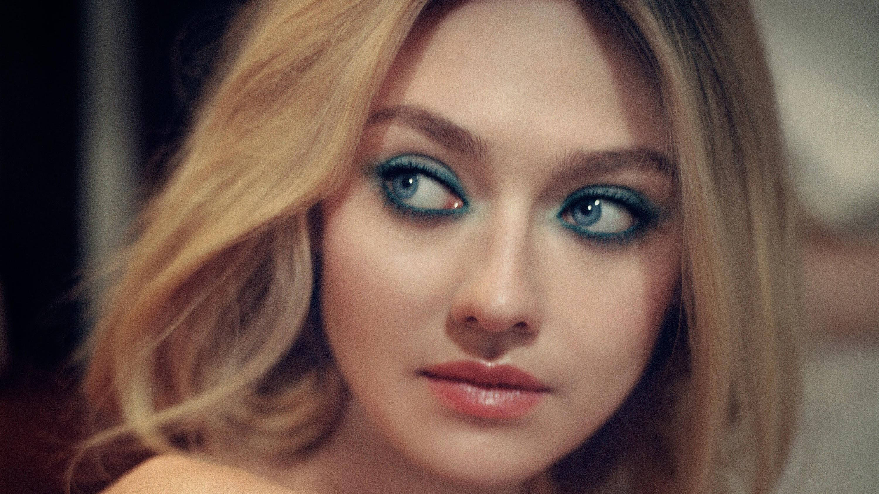 Celebrity 桌布 壁紙 — 一位擁有引人注目的藍色眼睛和金色頭髮的女性近距離肖像，直視鏡頭。