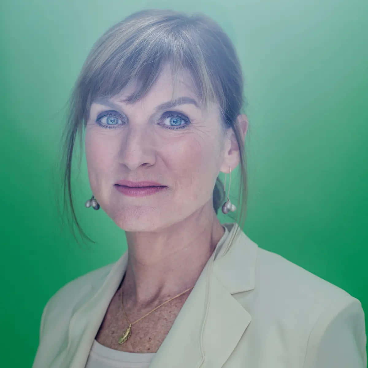 Fiona Bruce 桌布 壁紙 — 一位擁有引人注目的藍色眼睛和銀色頭髮的女性，在充滿活力的綠色漸變背景前溫柔微笑。