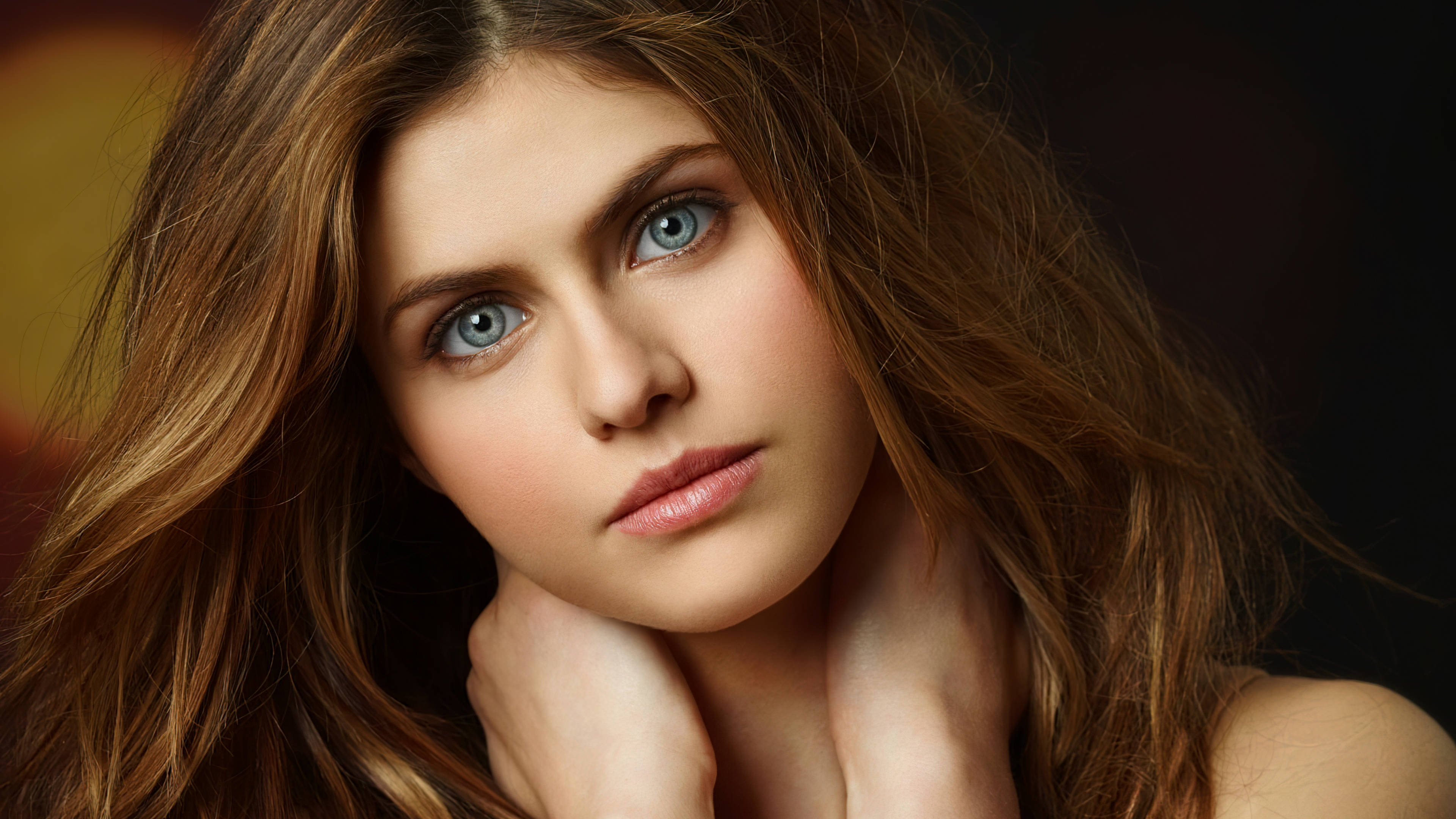 Alexandra Daddario 4K 桌布 壁紙 — 一位擁有引人注目的藍色眼睛和飄逸棕色頭髮的女性特寫肖像，直視觀看者。