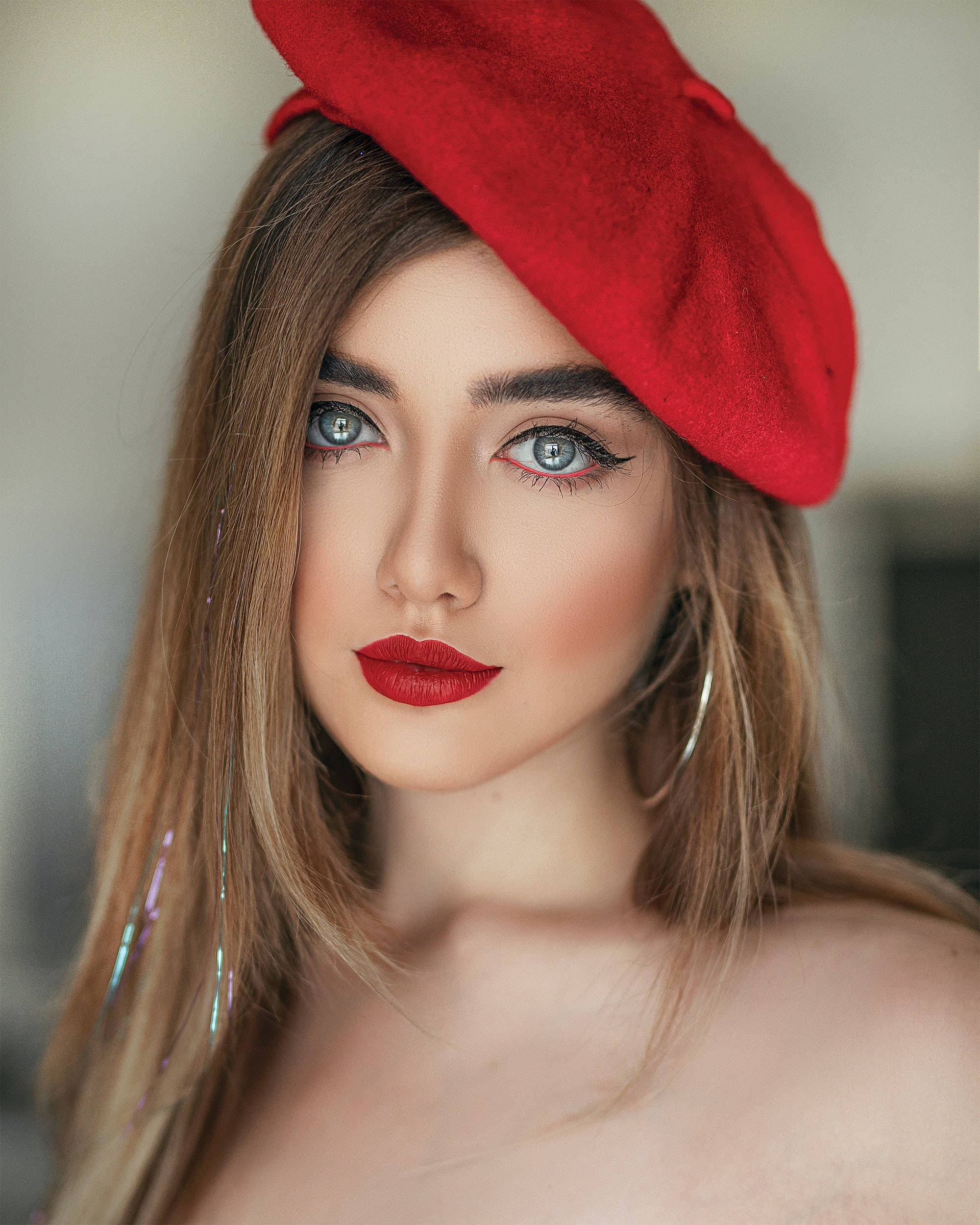 Beautiful Woman 桌布 壁紙 — 一位擁有引人注目的藍色眼睛的女性，在柔和光線的肖像中戴著大膽的紅色貝雷帽和相配的唇膏。
