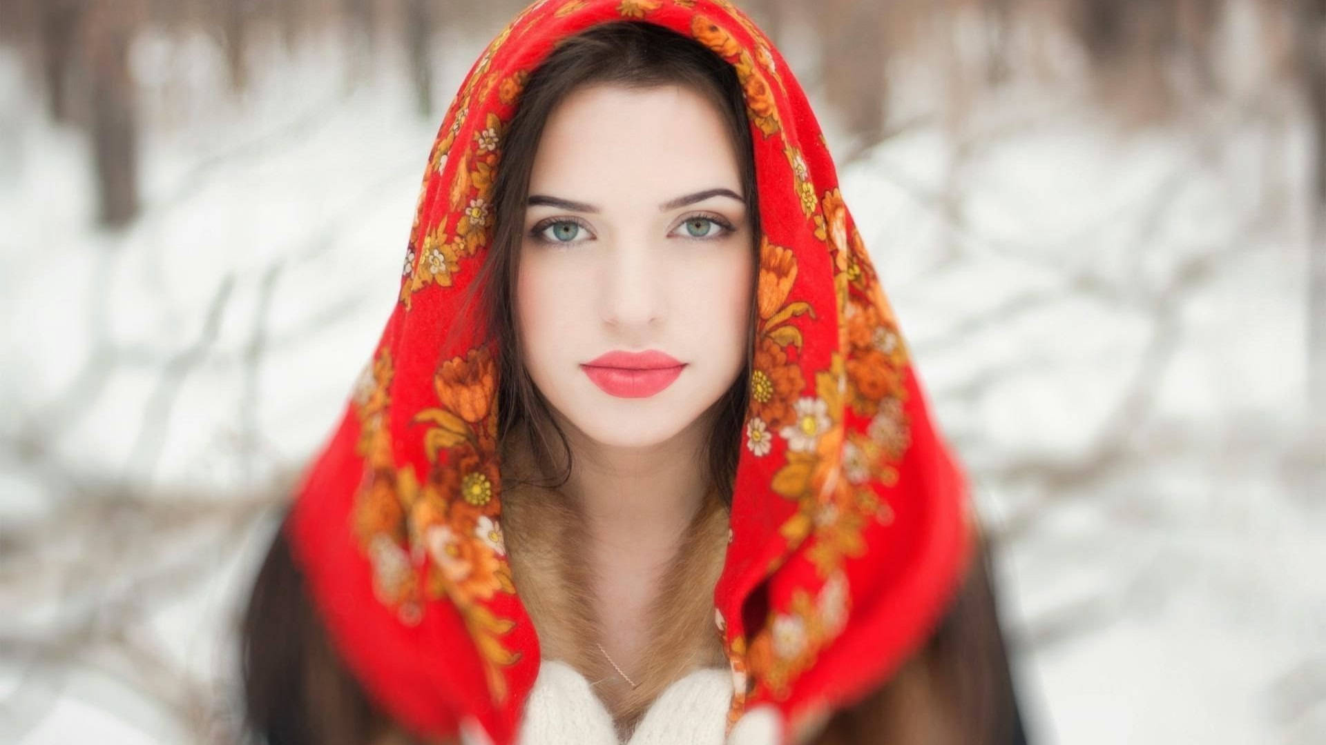 Russia 桌布 壁紙 — 一位擁有引人注目的藍色眼睛的女性，戴著鮮豔的紅色花卉頭巾，背景是白雪皚皚的冬季森林。