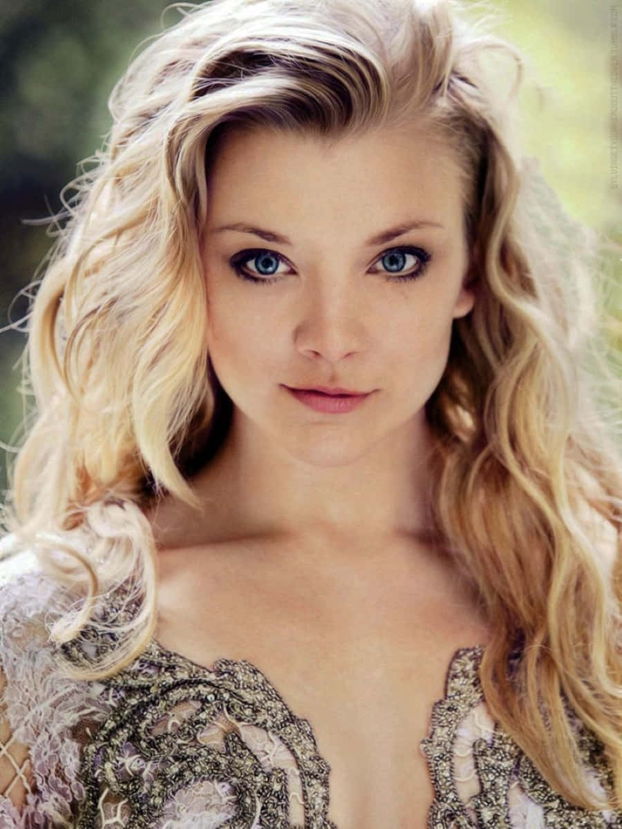 natalie dormer 桌布 壁紙 — 一位擁有引人注目藍眼睛和飄逸金髮的女性穿著華麗蕾絲上衣的特寫肖像。