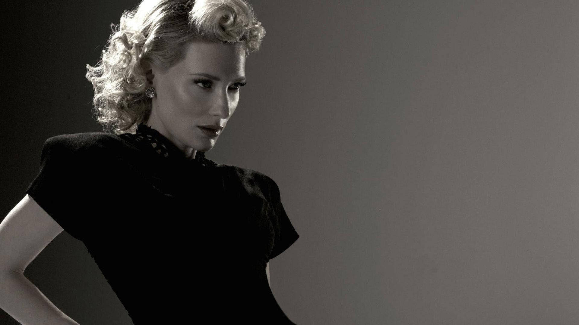 Cate 桌布 壁紙 — 一位擁有復古金色捲髮和黑色連衣裙的女性在灰色背景前以戲劇性的工作室燈光擺姿勢。