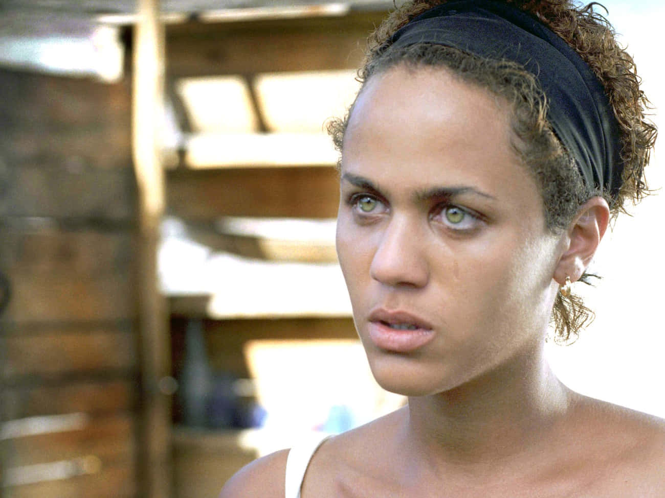 Nicole Ari Parker 桌布 壁紙 — 一位擁有捲髮和黑色頭帶的女性，在陽光照射的木質室內用綠色眼睛專注地凝視。