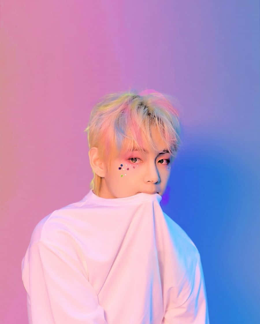 BTS V 動圖 桌布 壁紙 — 一位擁有柔和色調頭髮和彩色臉部亮粉的人，在粉紅與藍色漸變的攝影棚背景前擺姿勢。