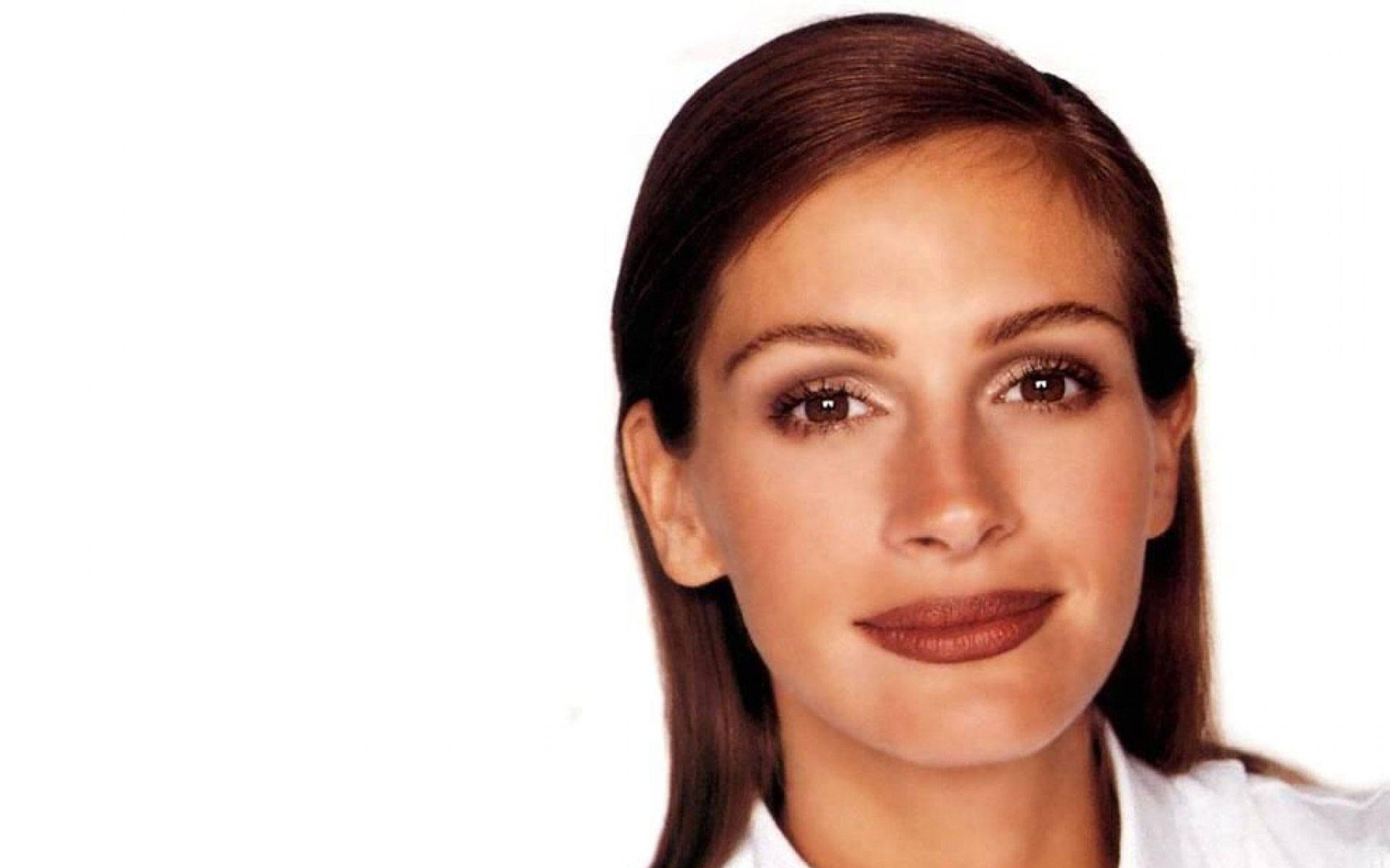 Julia Roberts 桌布 壁紙 — 一位擁有棕色頭髮和溫暖眼睛的女性，在純白色背景前柔和微笑的特寫肖像。