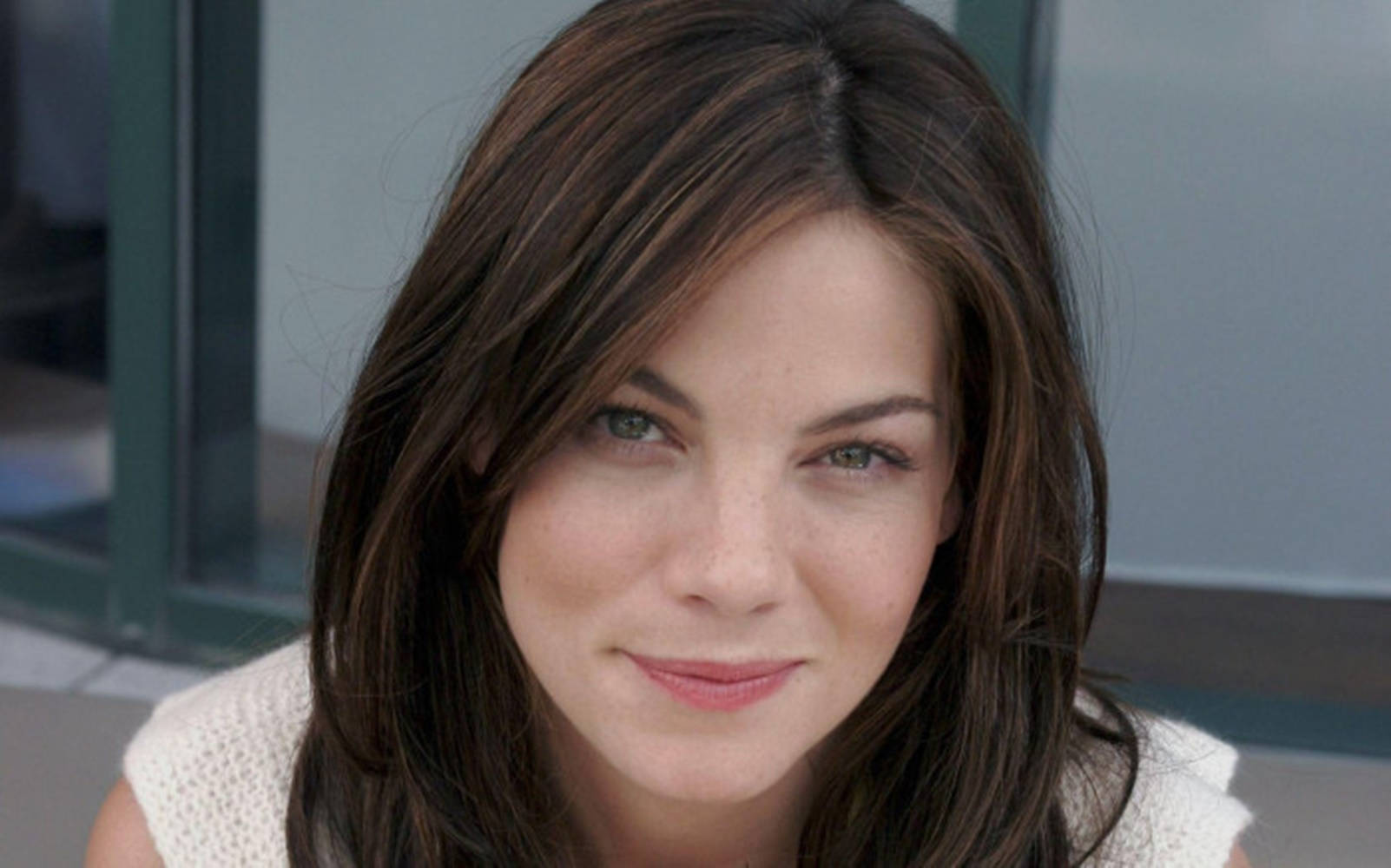 Michelle Monaghan 桌布 壁紙 — 一位擁有棕色頭髮和綠色眼睛的女性近距離肖像，對著鏡頭溫柔微笑。