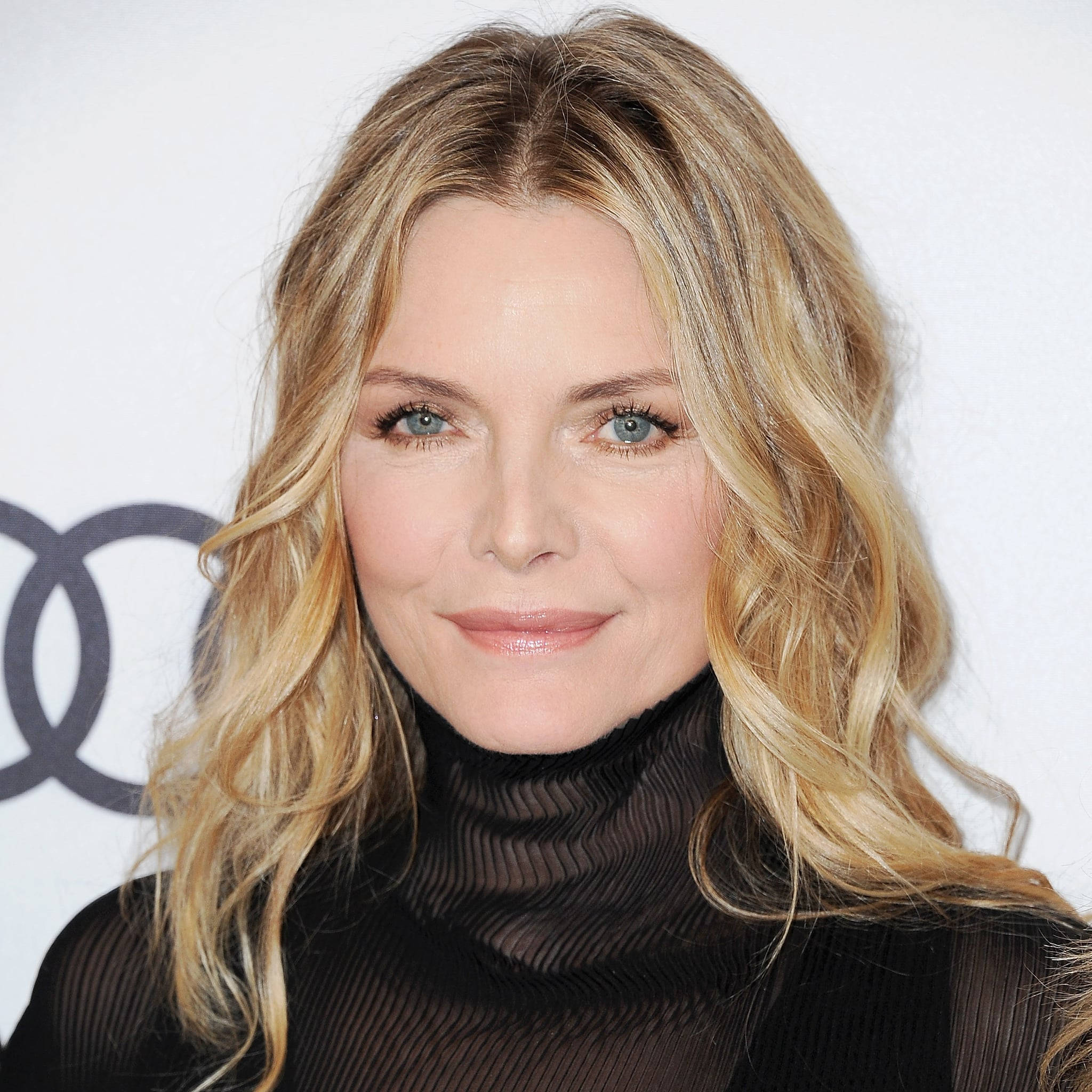 Celebrity 桌布 壁紙 — 一位擁有波浪形金髮和藍眼睛的女性，穿著黑色高領毛衣，以白色背景和奧迪標誌為背景的特寫肖像。