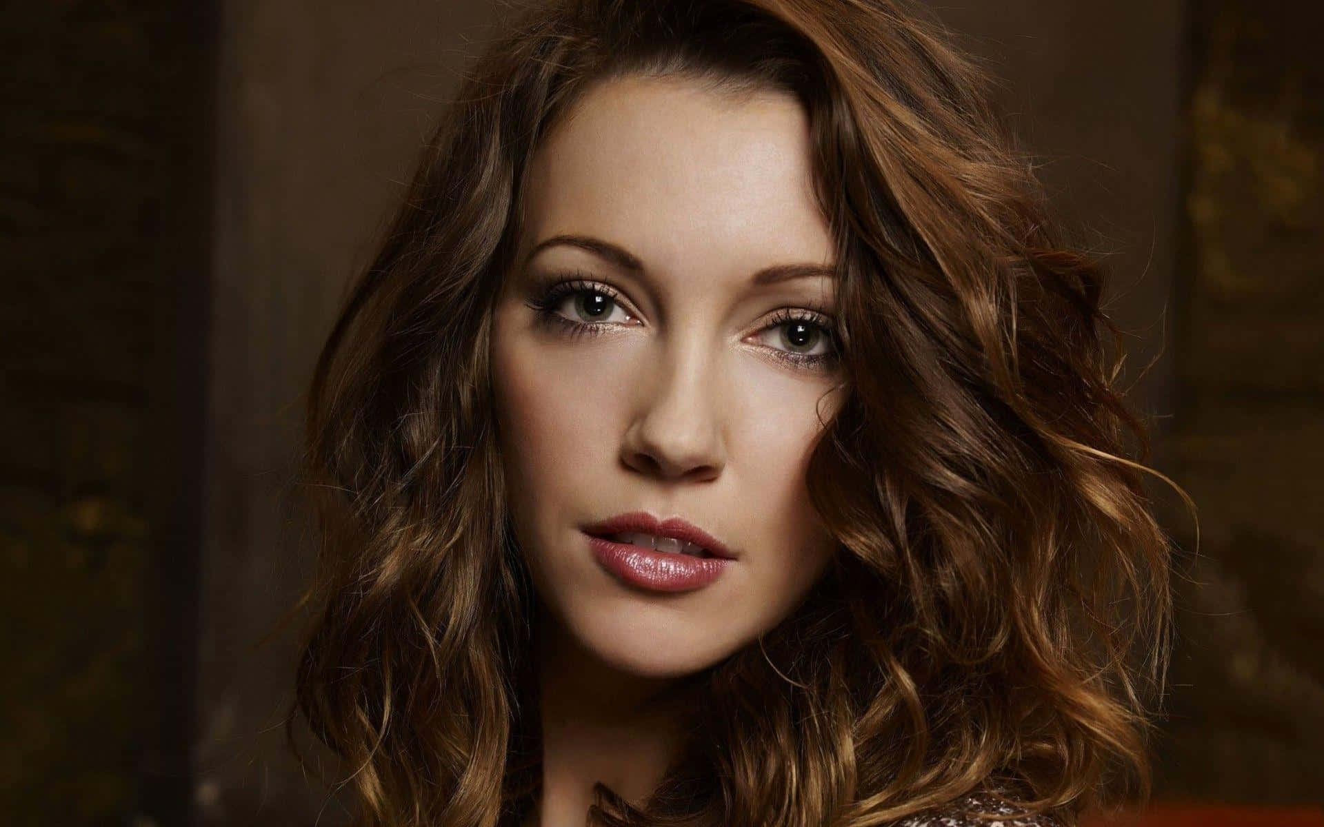 katie cassidy 桌布 壁紙 — 一位擁有波浪棕色頭髮和柔和妝容的女性特寫肖像，直視鏡頭。