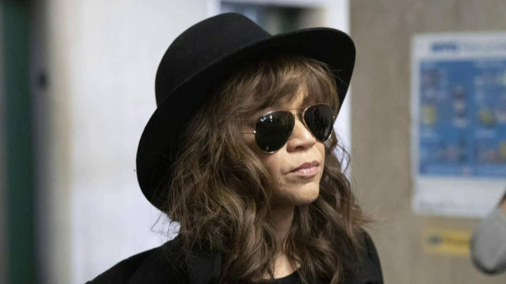 Celebrity 桌布 壁紙 — 一位擁有波浪棕色頭髮的女性，在公共室內空間戴著黑色軟呢帽和飛行員太陽眼鏡，側目而視。