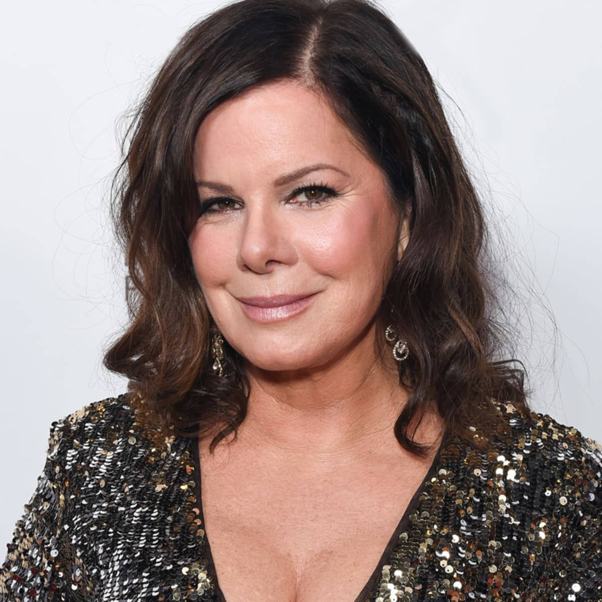Celebrity 桌布 壁紙 — 一位擁有波浪棕色頭髮的女性，穿著閃亮的金色和黑色亮片上衣，在純白色背景前溫柔微笑。