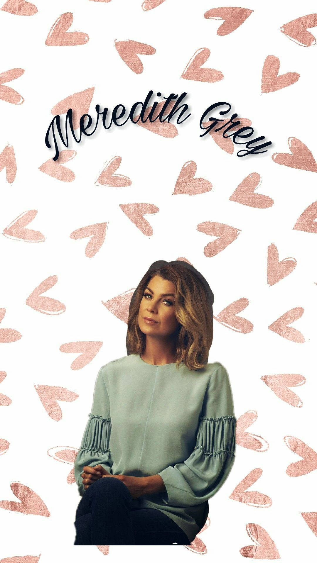 Ellen Pompeo 桌布 壁紙 — 一位擁有波浪棕色頭髮的女性平靜地坐在白色背景前，背景充滿散落的玫瑰金色心形和草書名字Meredith Grey。