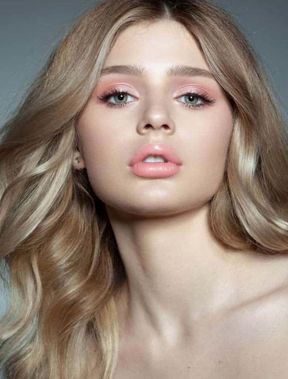 Spring Makeup 桌布 壁紙 — 一位擁有波浪金髮和柔和粉紅妝容的女性，在柔和灰色背景下的特寫肖像。