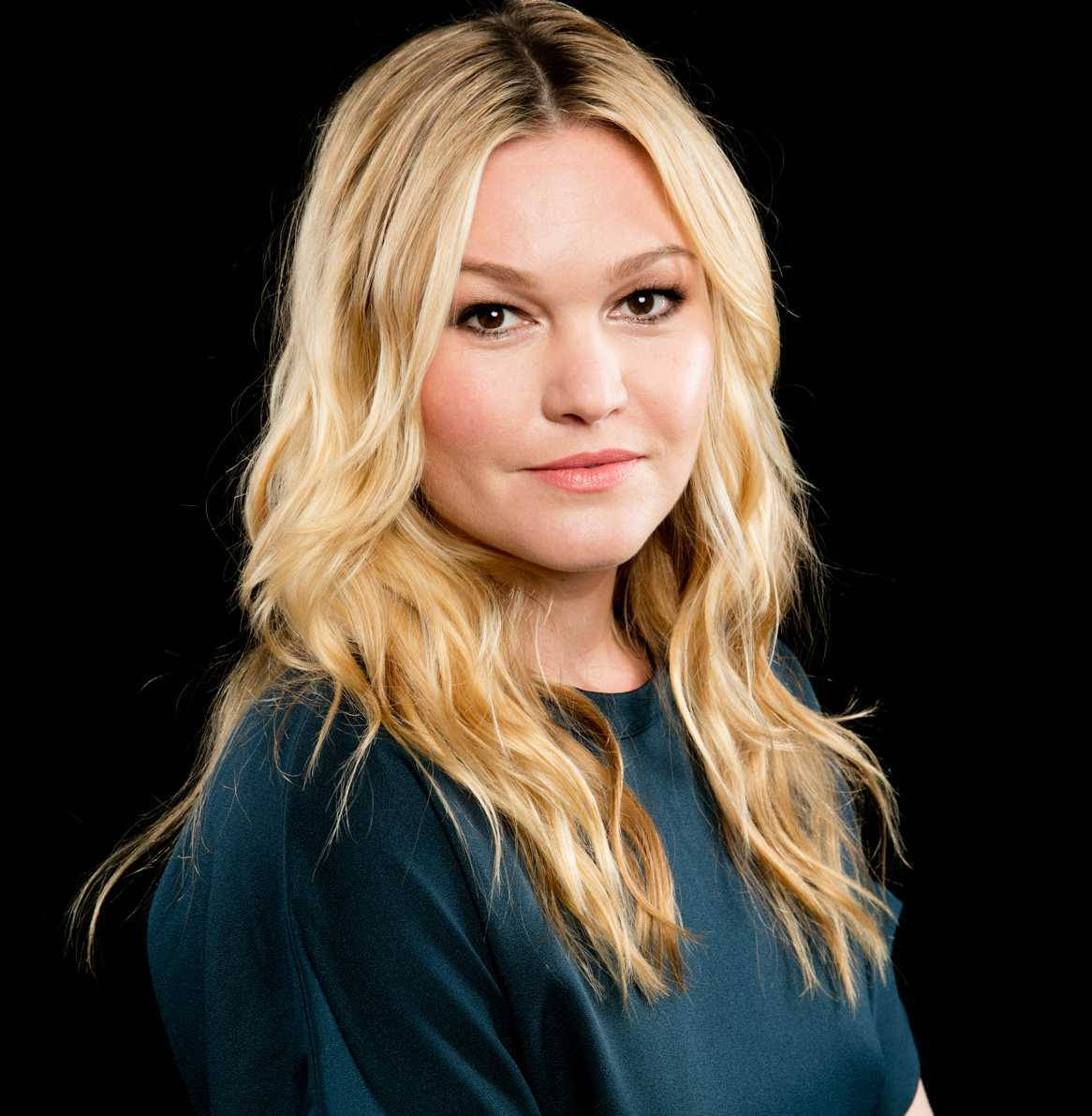 Celebrity 桌布 壁紙 — 一位擁有波浪金髮和溫柔微笑的女性，在黑色背景前穿著青綠色上衣。