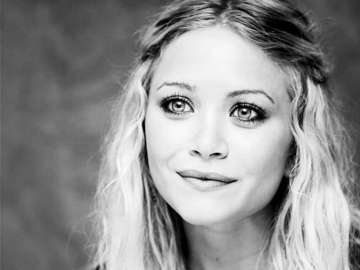 Mary Kate Olsen 桌布 壁紙 — 一位擁有波浪金髮和溫柔微笑的女性黑白肖像，直視鏡頭。