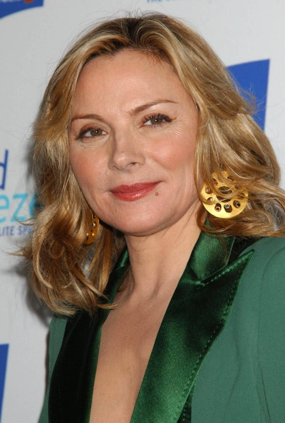 Celebrity 桌布 壁紙 — 一位擁有波浪金髮和金色耳環的女性，穿著綠色緞面西裝外套在活動中微笑。