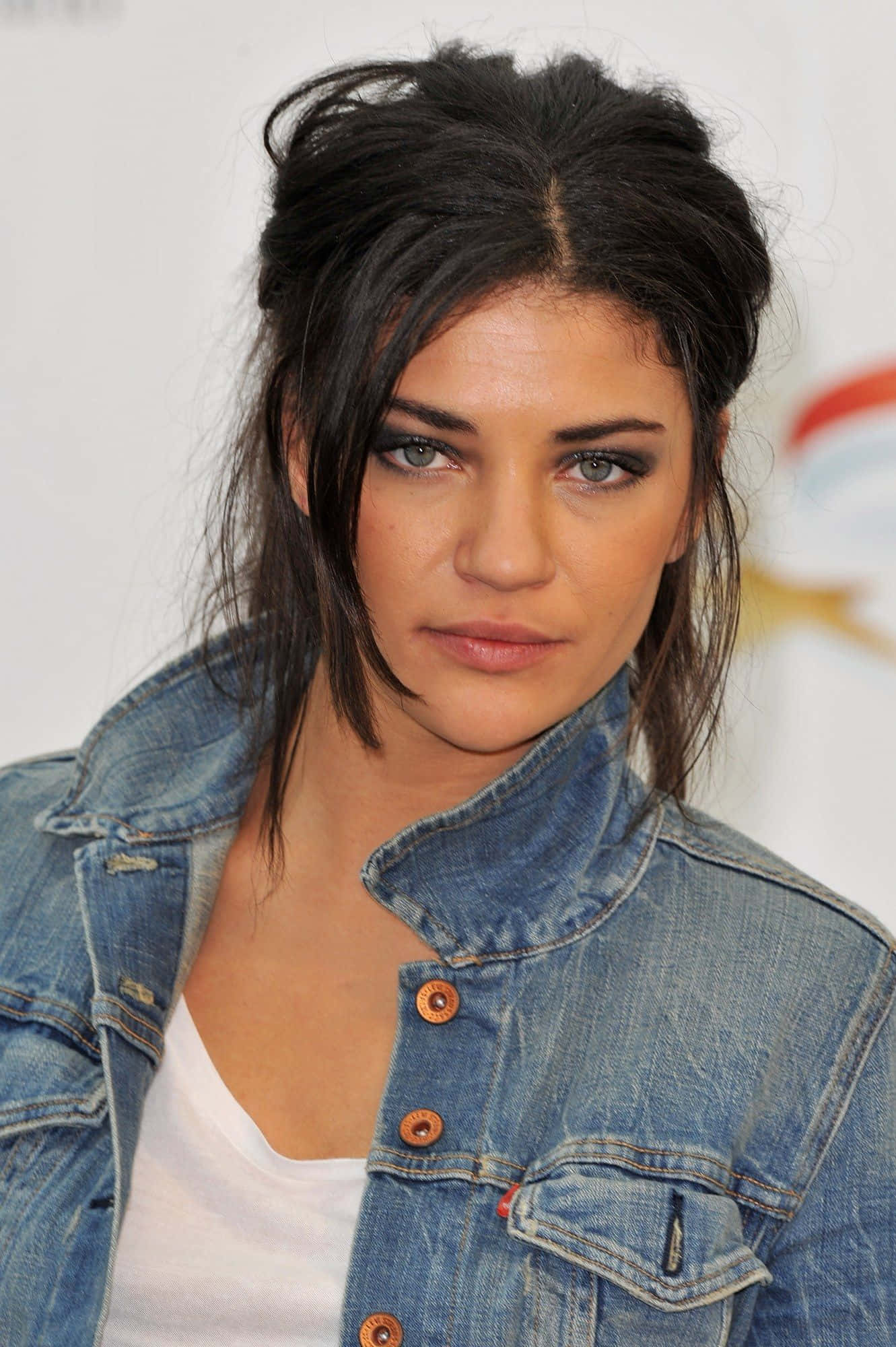 jessica szohr 桌布 壁紙 — 一位擁有深色凌亂頭髮和煙燻妝眼睛的女性，穿著牛仔外套內搭白色上衣，專注地凝視著。