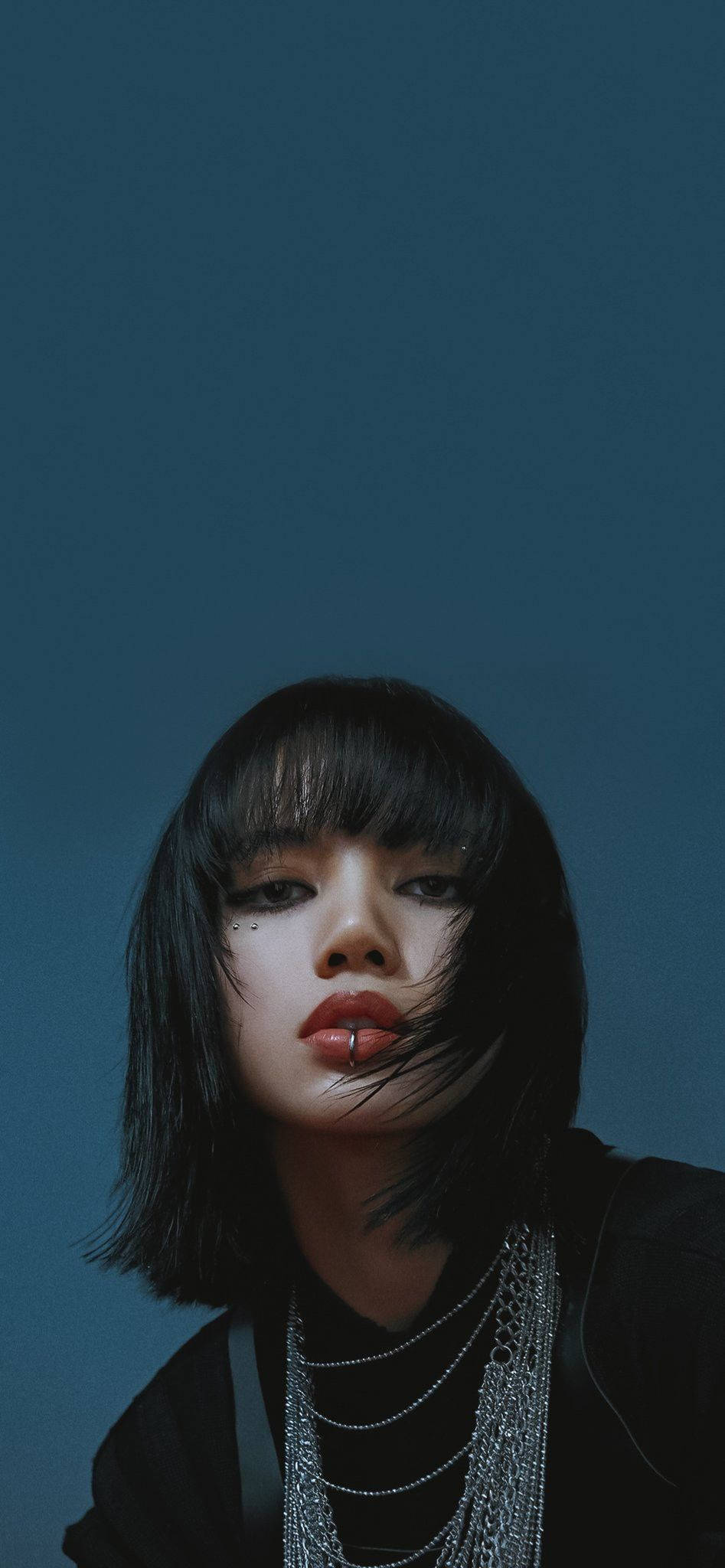 Lalisa 桌布 壁紙 — 一位擁有深色鮑伯頭和紅唇的年輕女性，在深藍色背景下強烈凝視。