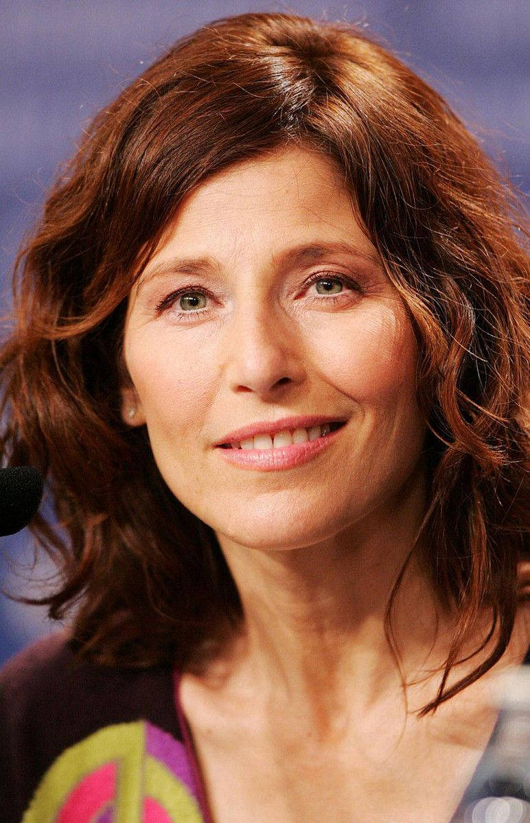 Celebrity 桌布 壁紙 — 一位擁有溫暖棕色頭髮和溫柔微笑的女性特寫肖像，背景為模糊的藍色。