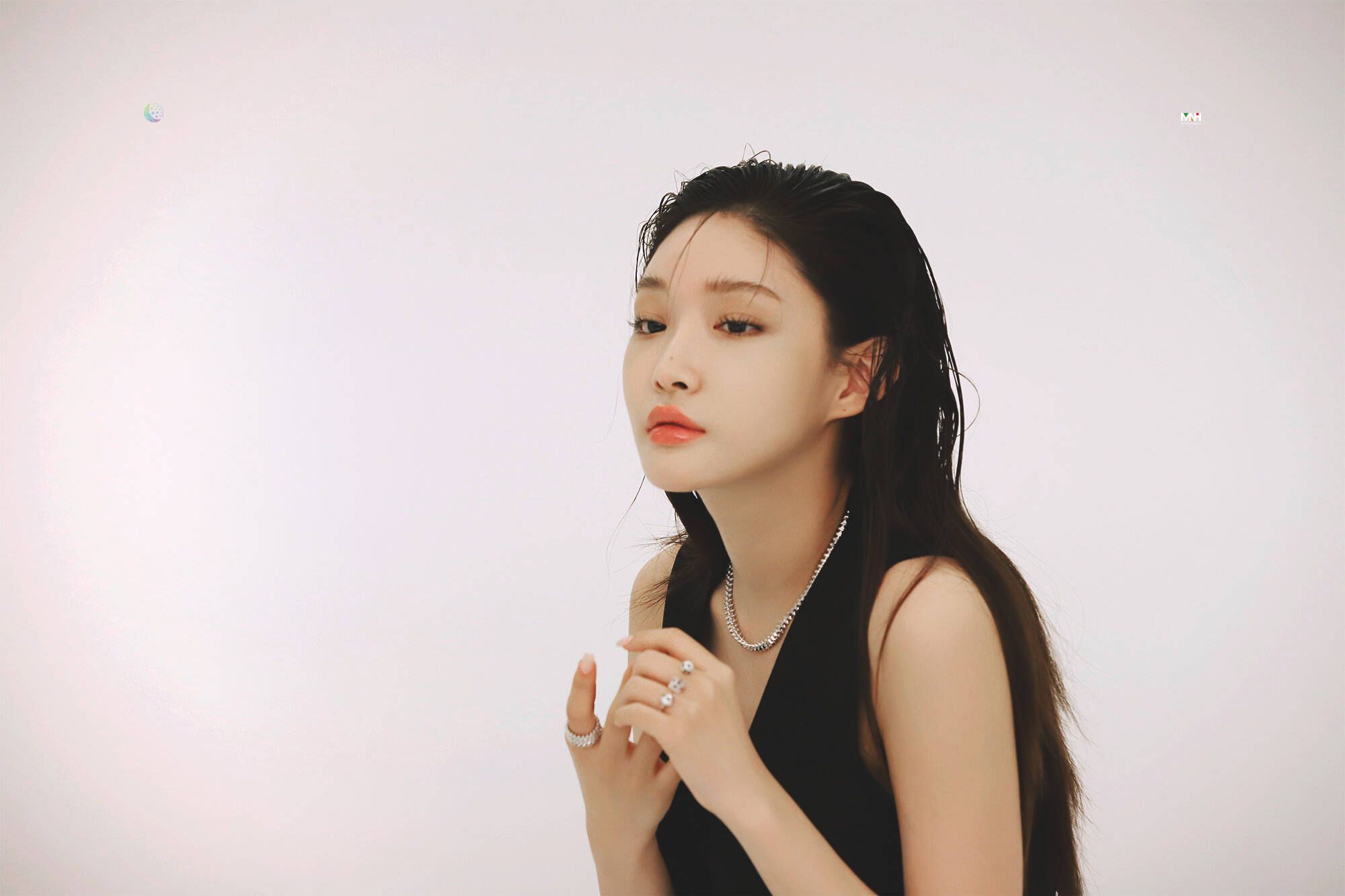 Chungha 桌布 壁紙 — 一位擁有濕黑髮和紅唇的女性，在白色背景前若有所思地凝視，身穿黑色上衣和銀色首飾。