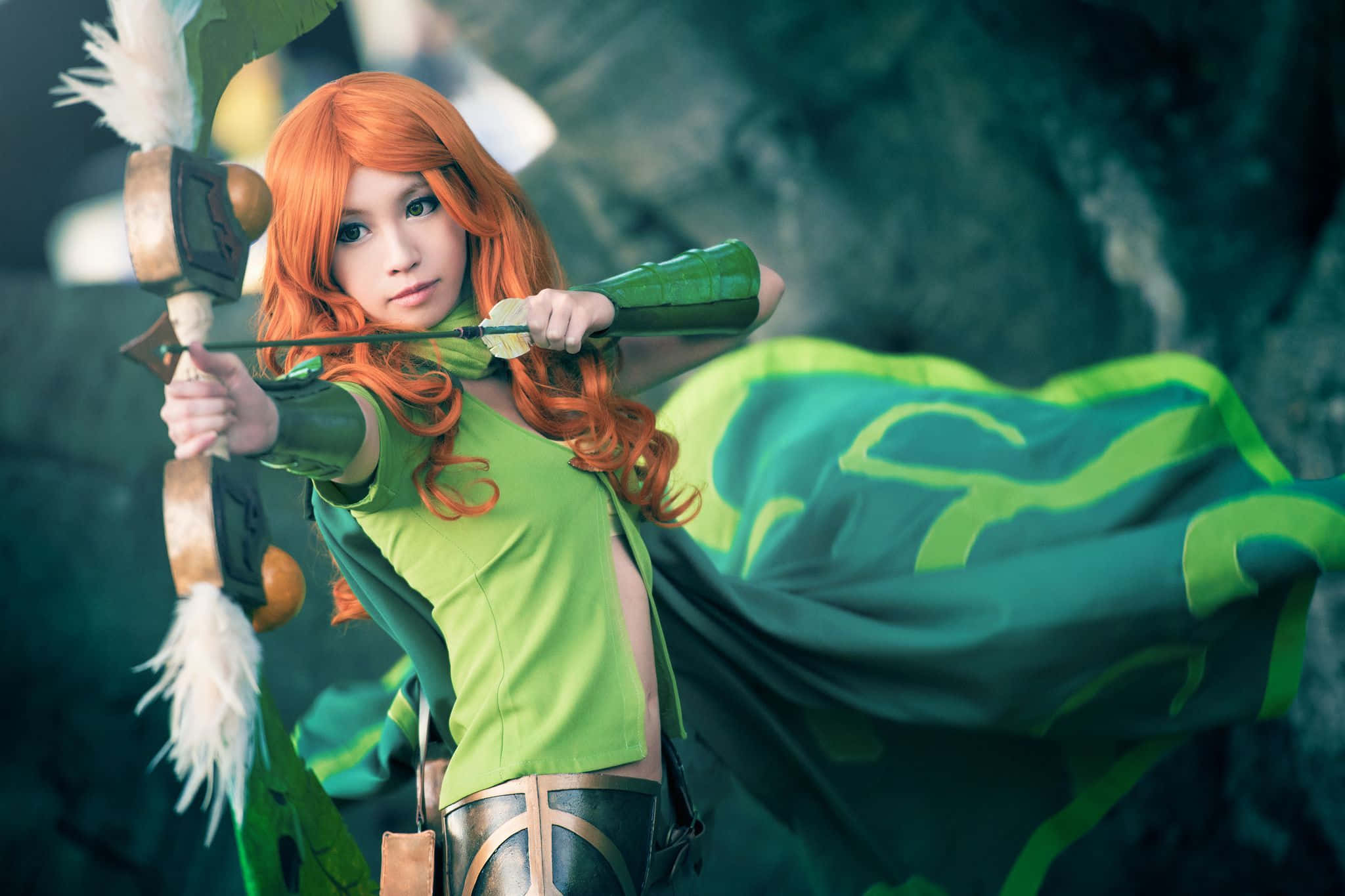 Windranger 桌布 壁紙 — 一位擁有火橙色頭髮和綠色服裝的角色扮演者在洞穴中拉弓，布料飄逸，箭矢帶有羽毛。