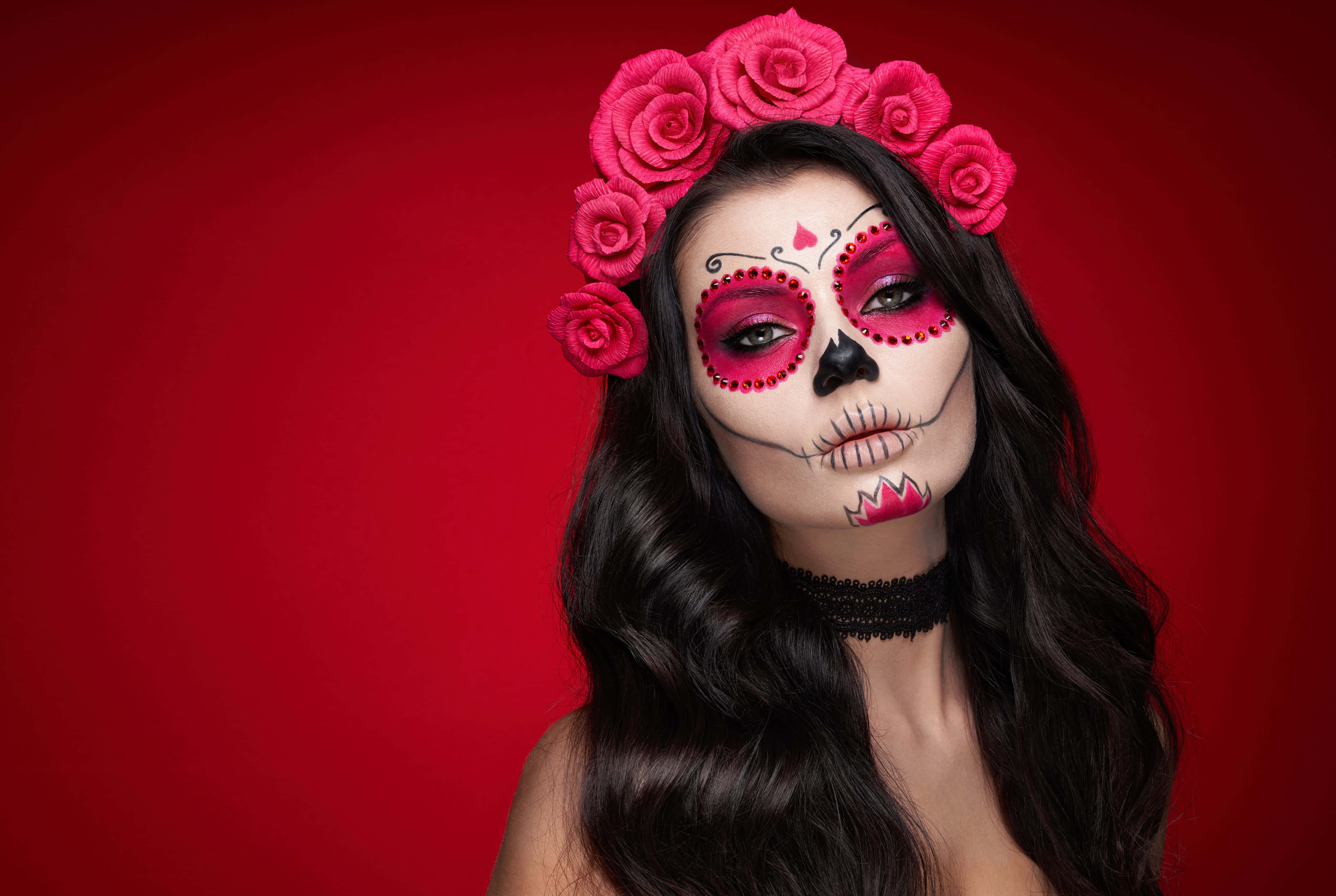 Halloween Face Paint 桌布 壁紙 — 一位擁有精緻糖骷髏妝容和粉紅玫瑰冠的女性，在鮮紅色的背景前擺姿勢。