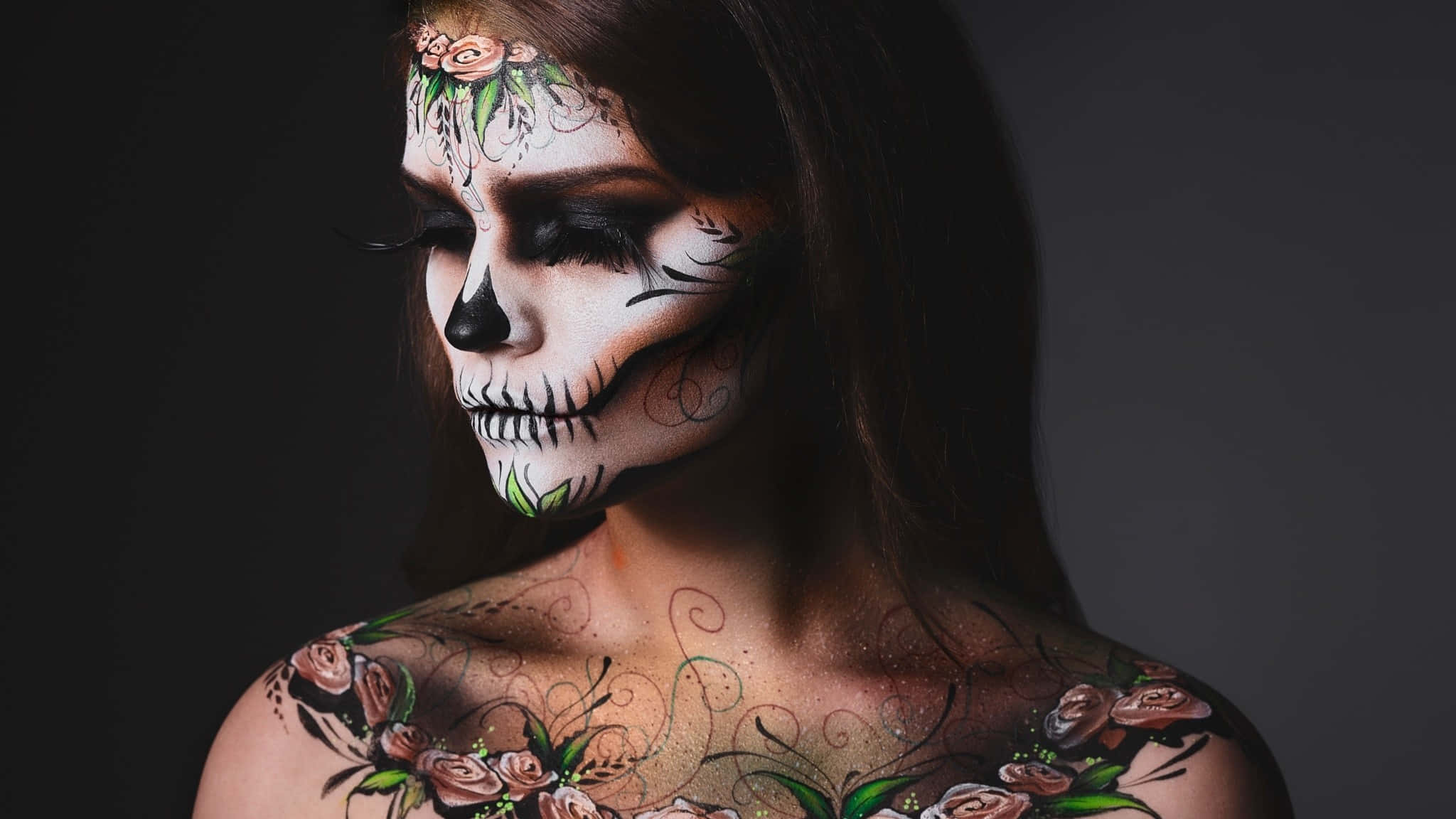Halloween Tattoos 桌布 壁紙 — 一位擁有精緻糖骷髏妝容和花卉刺青的女性，在黑暗背景中閃耀。