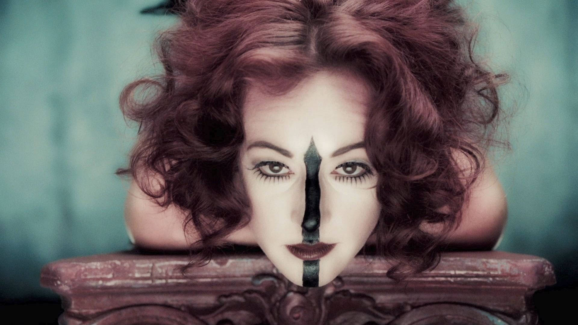 American Horror Story 桌布 壁紙 — 一位擁有紅色捲髮的女性倚靠在華麗的木質邊緣上，她的臉被一條黑色垂直條紋垂直分割。