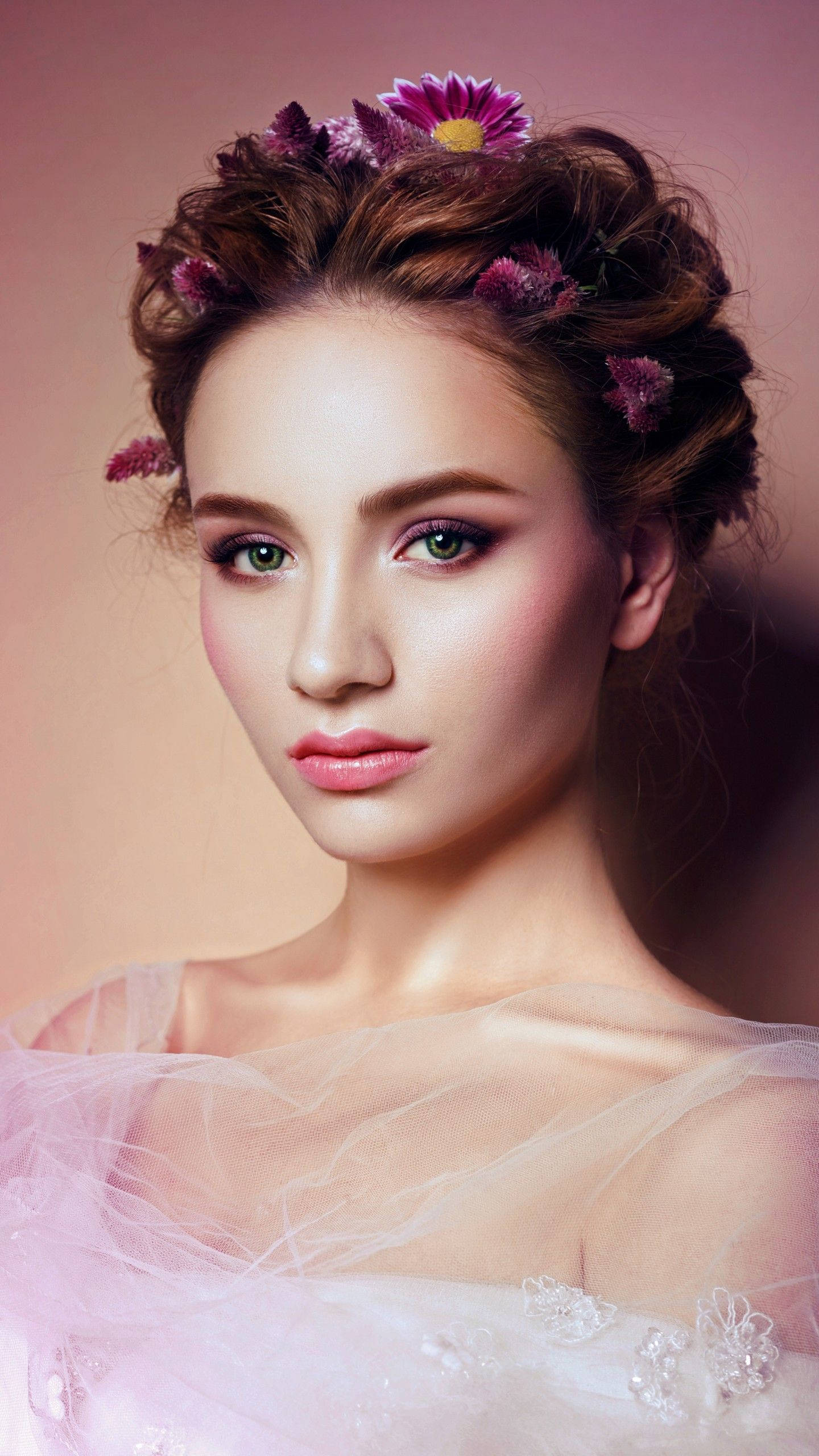 Beautiful Woman 桌布 壁紙 — 一位擁有綠色眼睛和花卉頭飾的女性在柔和的粉紅色工作室肖像中溫柔地凝視。