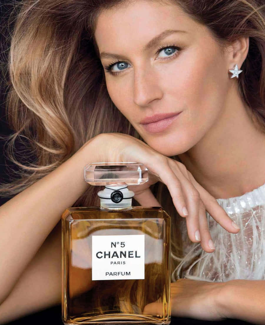 Chanel 桌布 壁紙 — 一位擁有藍色眼睛和星星耳環的女性，在深色背景前輕輕將手放在經典的Chanel No5香水瓶上。