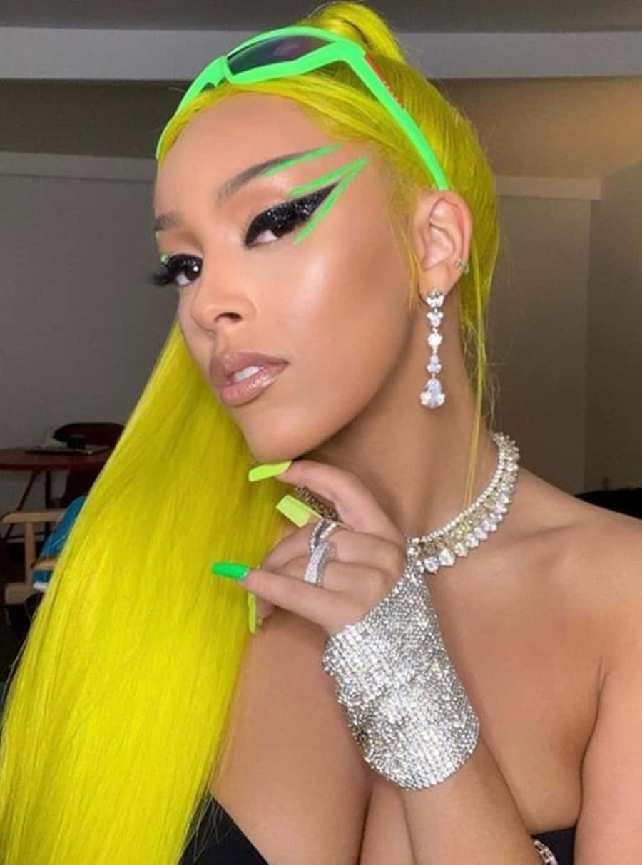 Doja Cat 桌布 壁紙 — 一位擁有螢光黃色頭髮、頭上戴著相配綠色太陽眼鏡的女性，自信地擺出姿勢，佩戴著閃閃發光的鑽石珠寶。