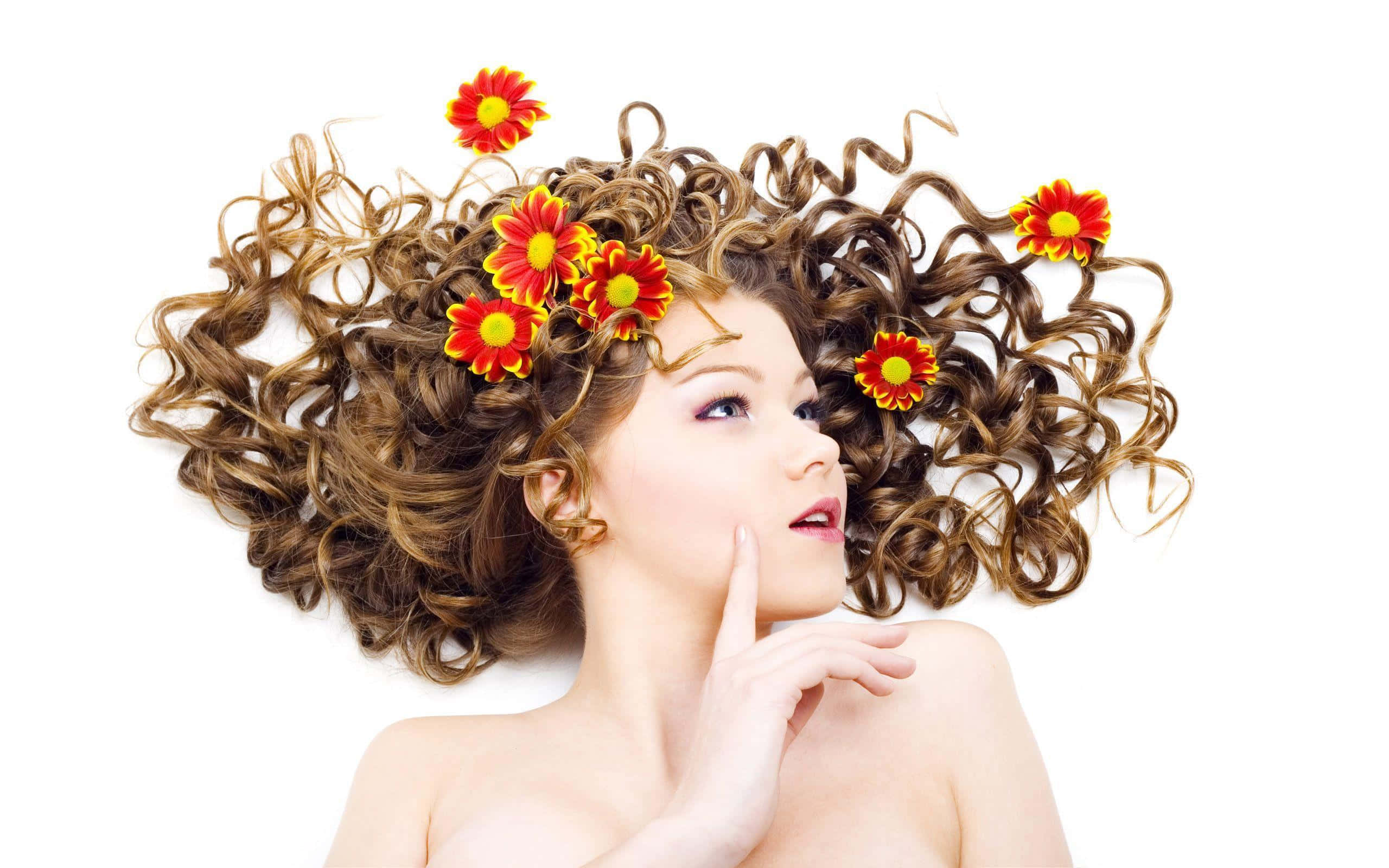 Hairstyle 桌布 壁紙 — 一位擁有豐盈捲曲頭髮、點綴著鮮豔紅黃花朵的女性，在純白背景上向上凝視。