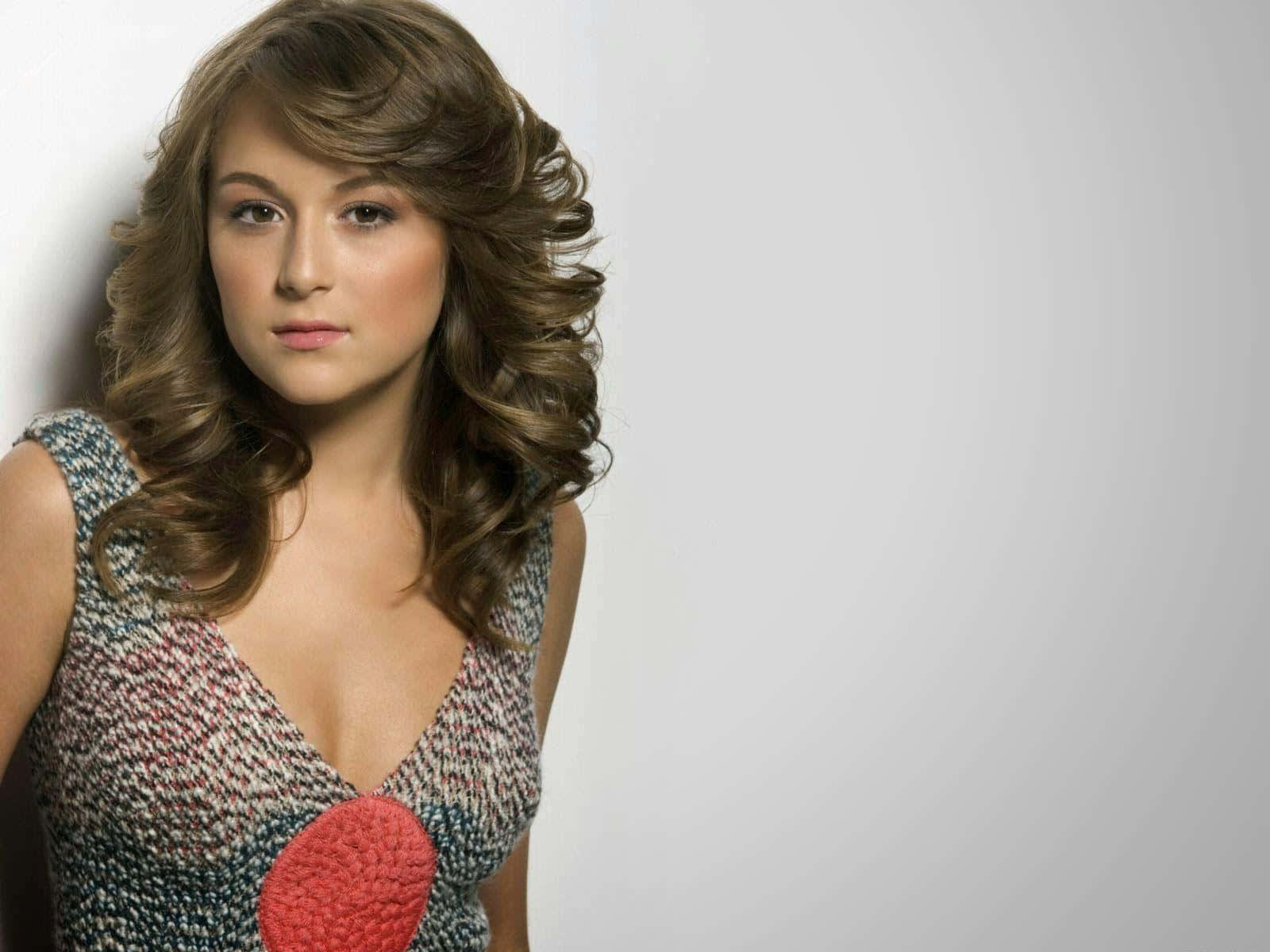 Alexa Penavega 桌布 壁紙 — 一位擁有豐盈棕色捲髮的女性，身穿帶有紅色圓形細節的紋理連衣裙，背景為純白色。