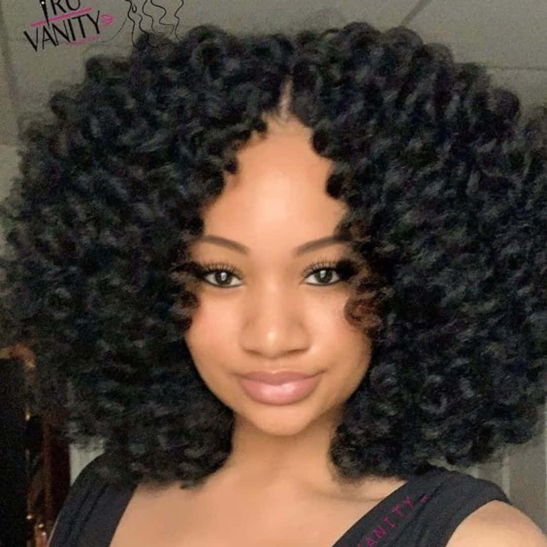 Curly Hair 桌布 壁紙 — 一位擁有豐盈深色捲髮的女性在特寫肖像中對著鏡頭溫柔微笑。