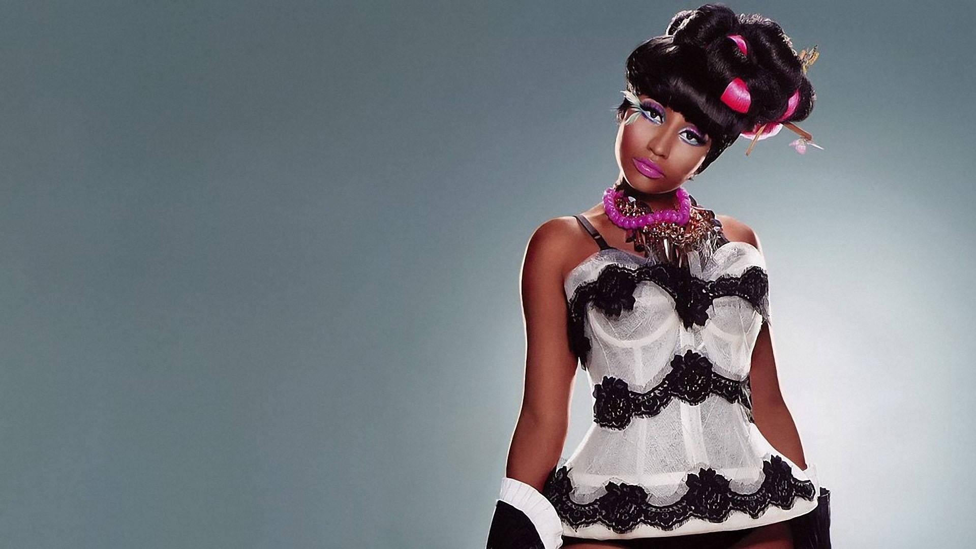 Nicki 桌布 壁紙 — 一位擁有豐盈黑髮、飾有粉紅色髮捲的女性，在柔和的灰色背景下，自信地穿著黑白蕾絲服裝擺姿勢。