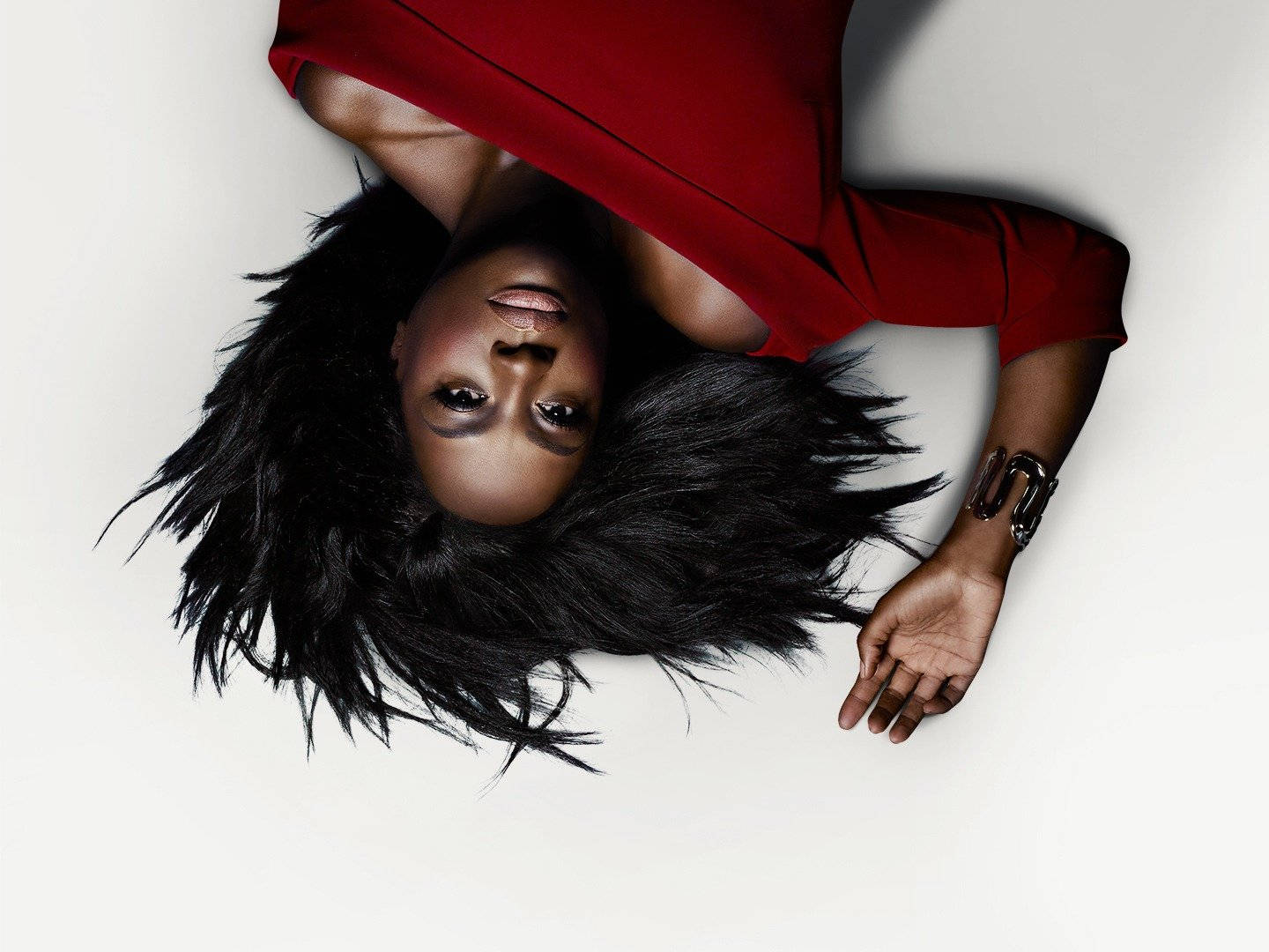 How To Get Away With Murder 桌布 壁紙 — 一位擁有豐盈黑髮和紅色連衣裙的女性仰臥在純白背景上，以沉穩的表情向上凝視。