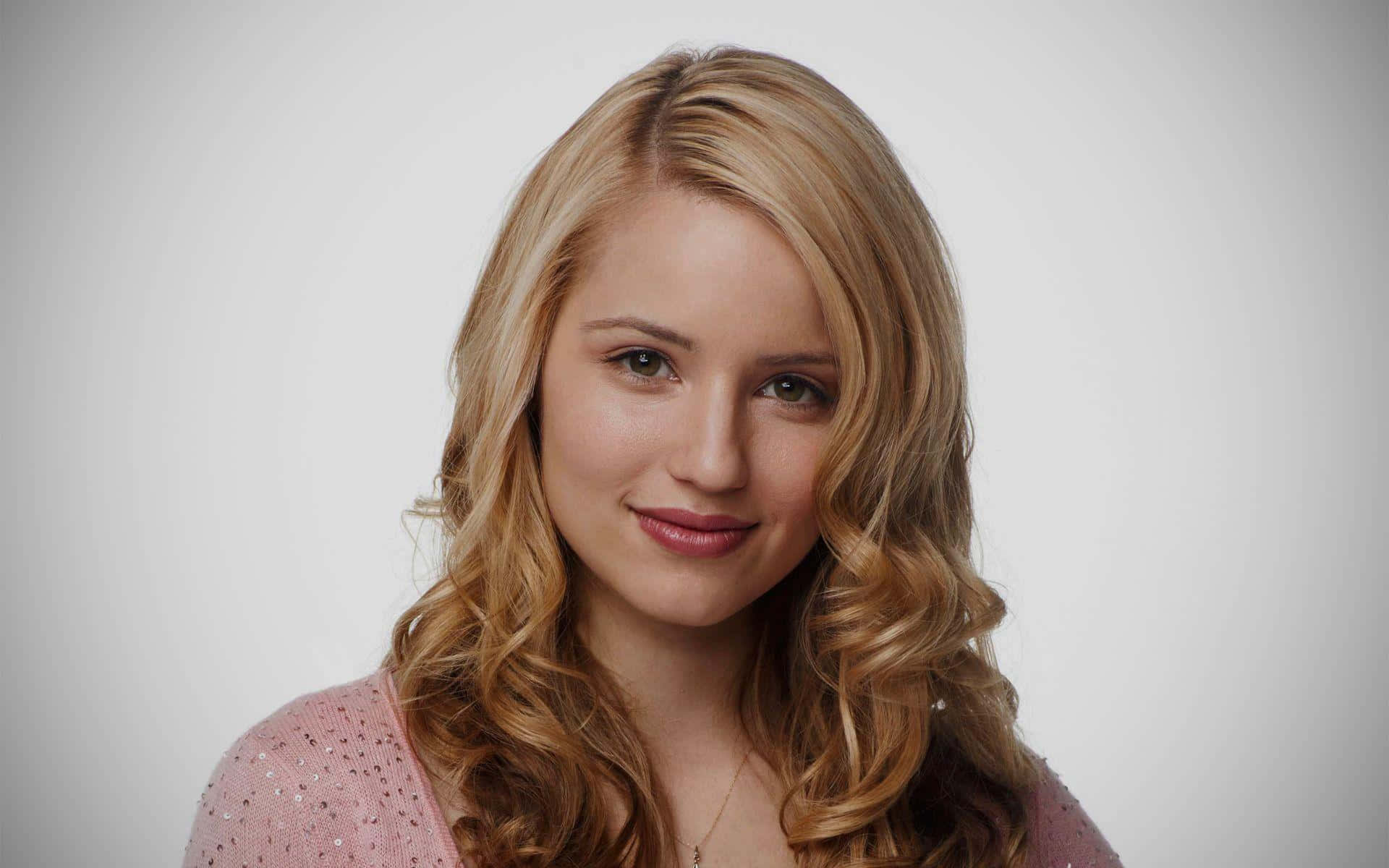 dianna agron 桌布 壁紙 — 一位擁有金色捲髮和溫柔微笑的年輕女性，在純白背景前穿著粉紅色閃亮上衣。