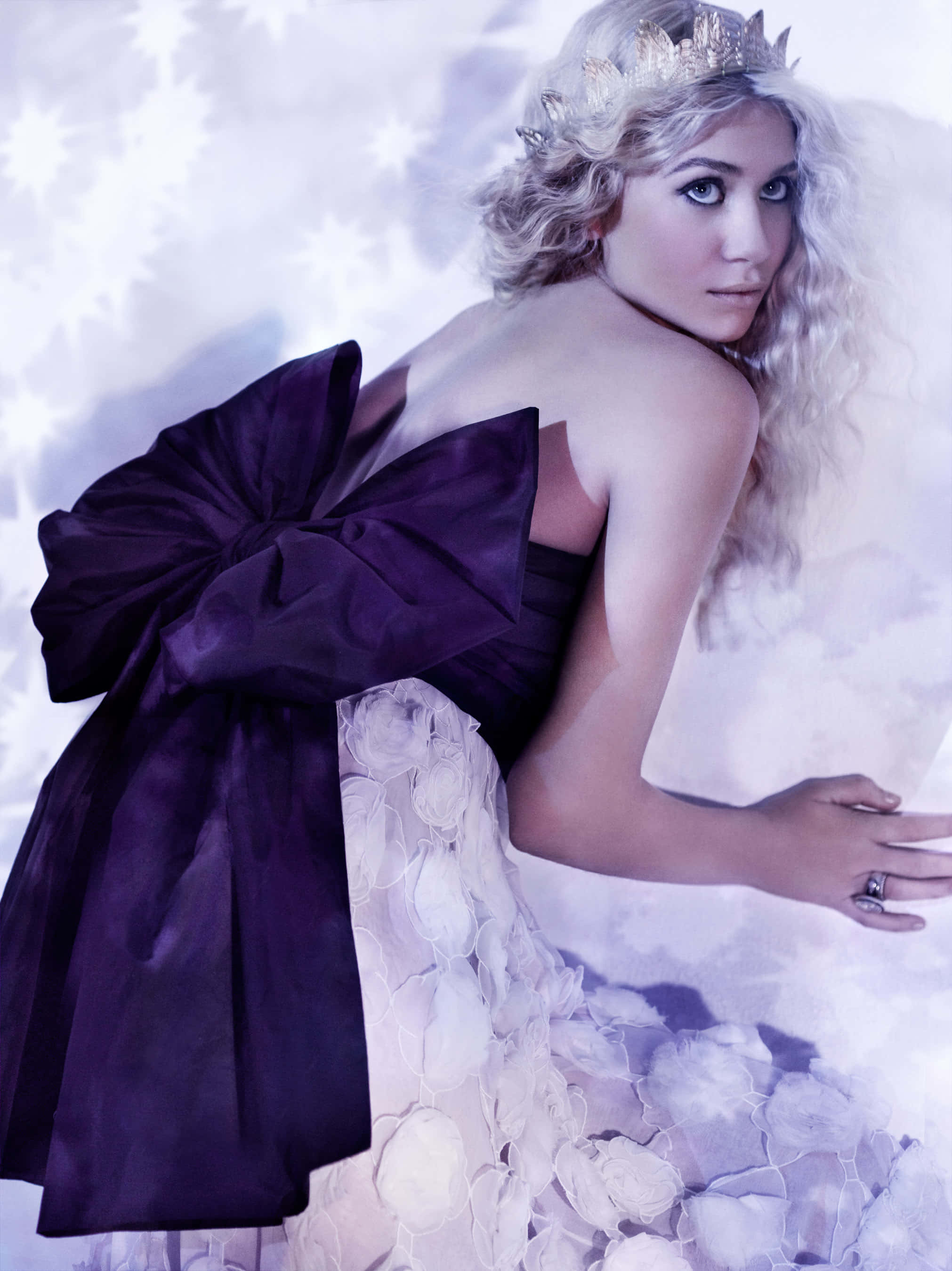 ashley olsen 桌布 壁紙 — 一位擁有金色捲髮和銀色皇冠的女性，在星空背景下穿著紫色蝴蝶結和白色花卉長袍。