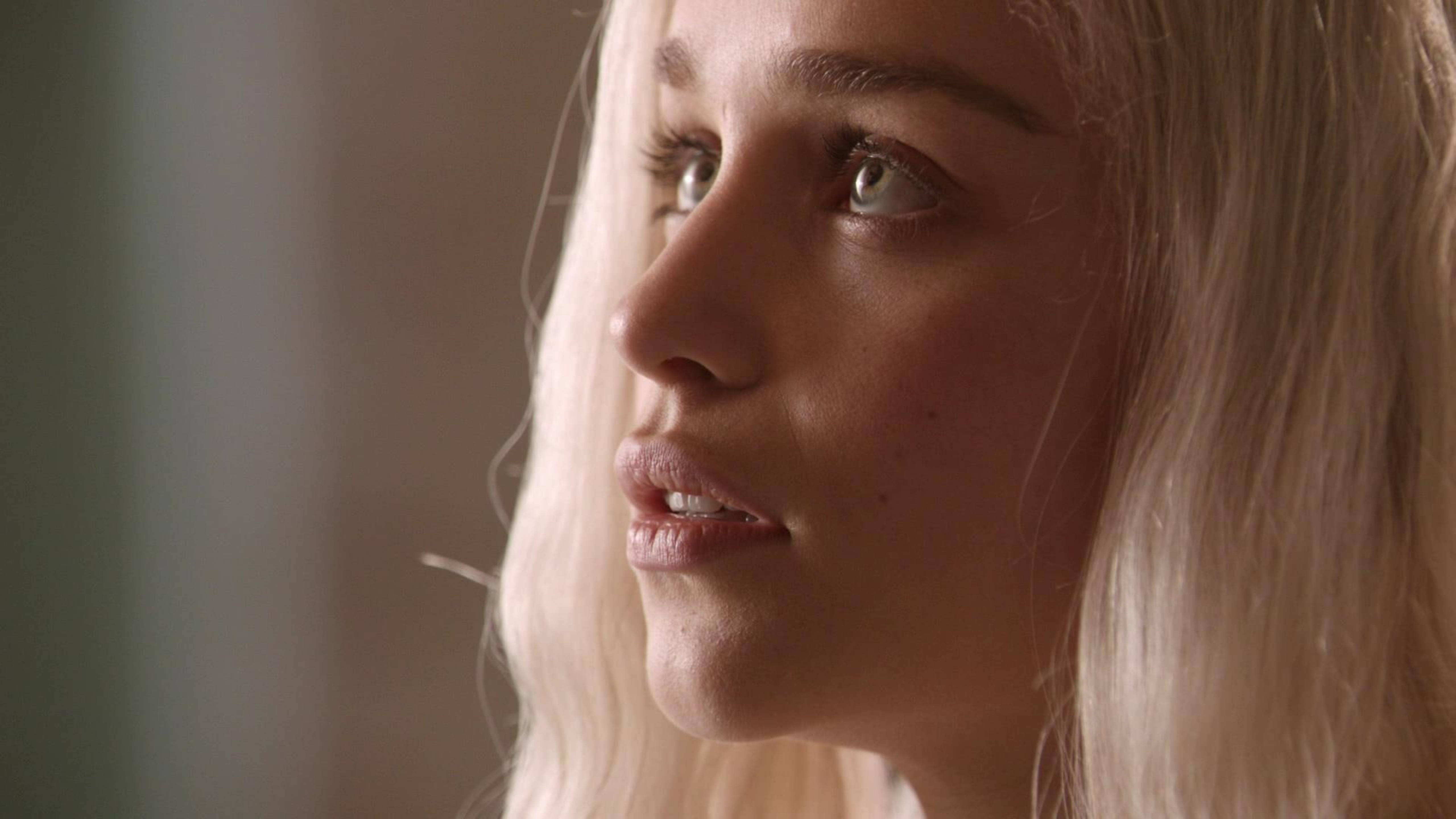 daenerys 桌布 壁紙 — 一位擁有鉑金色頭髮和綠色眼睛的女性在柔和溫暖的光線中若有所思地側視的特寫肖像。