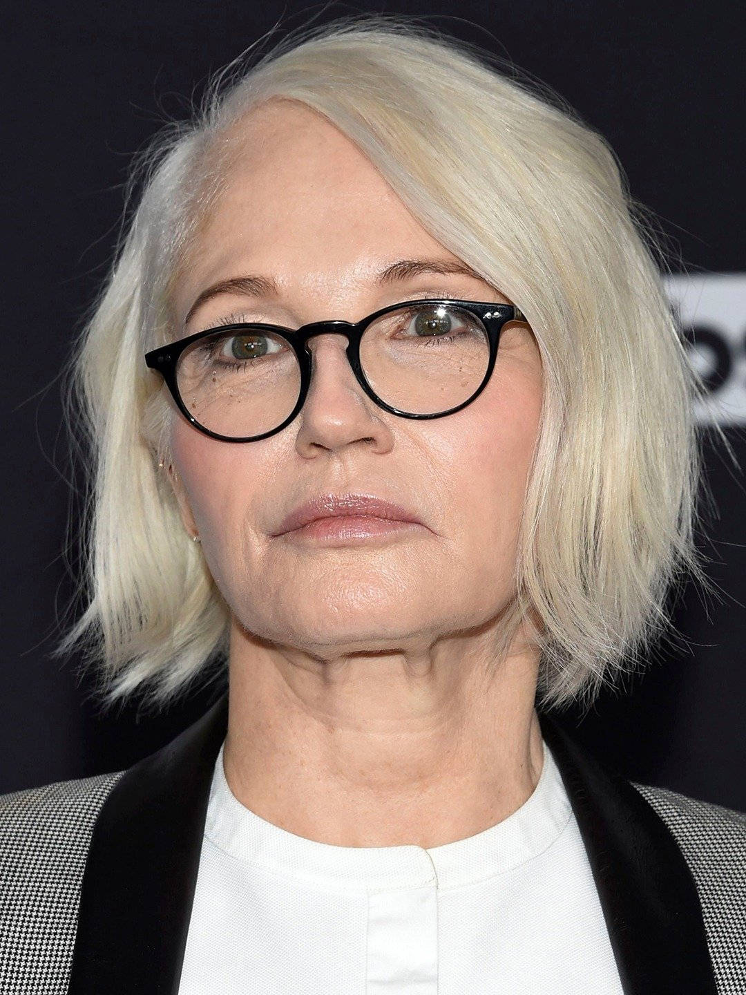 Celebrity 桌布 壁紙 — 一位擁有鉑金色頭髮和黑色框眼鏡的女性穿著白色襯衫和圖案西裝外套的特寫肖像。